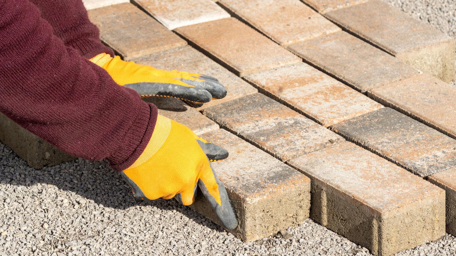 Una persona lastrica il vialetto del giardino con pietre per selciati.