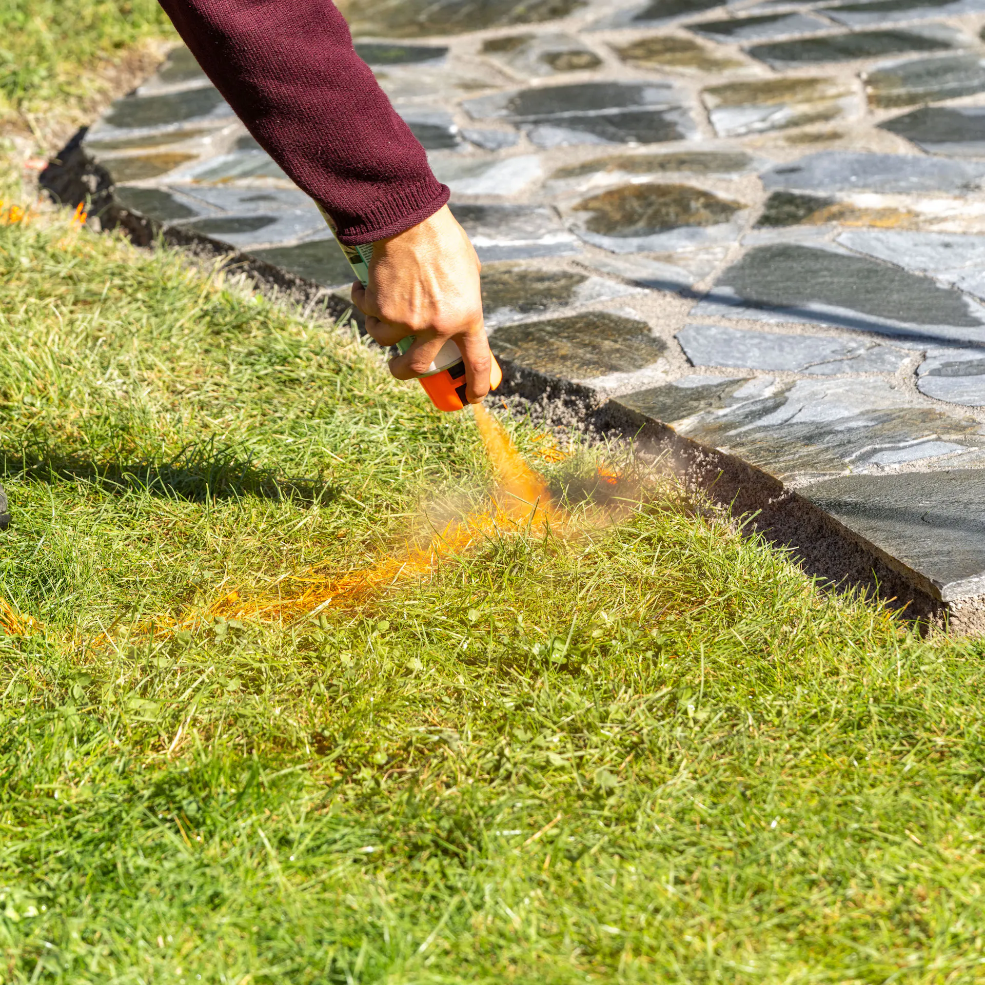 Muž stříká trávník značkovacím sprejem
