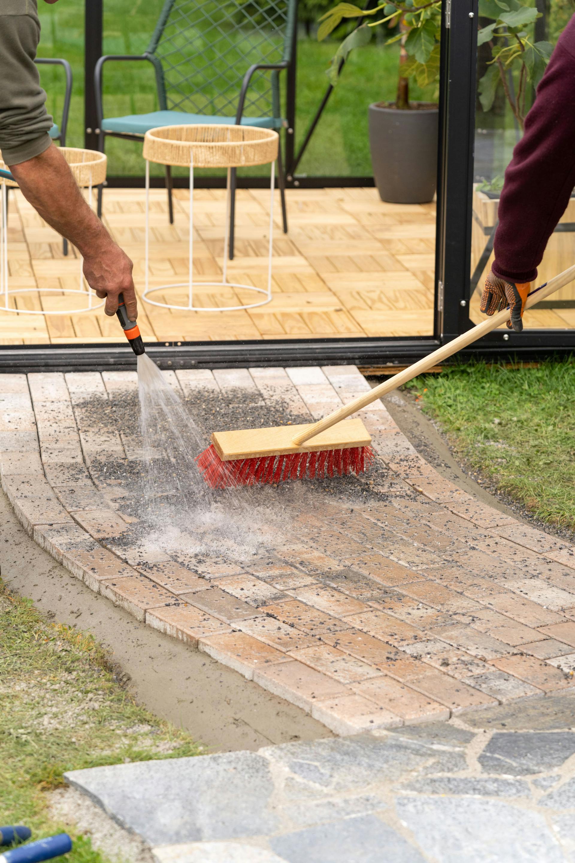 Un sentiero lastricato con pietrisco viene innaffiato con un tubo da giardino