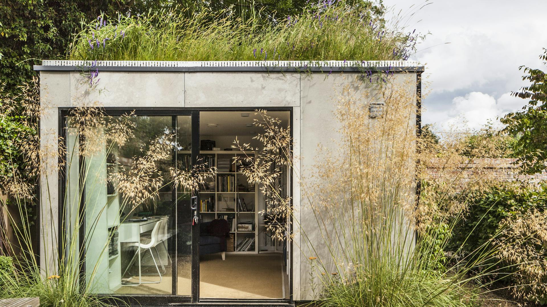 Vor einem Bungalow wachsen verschiedene Gräser.