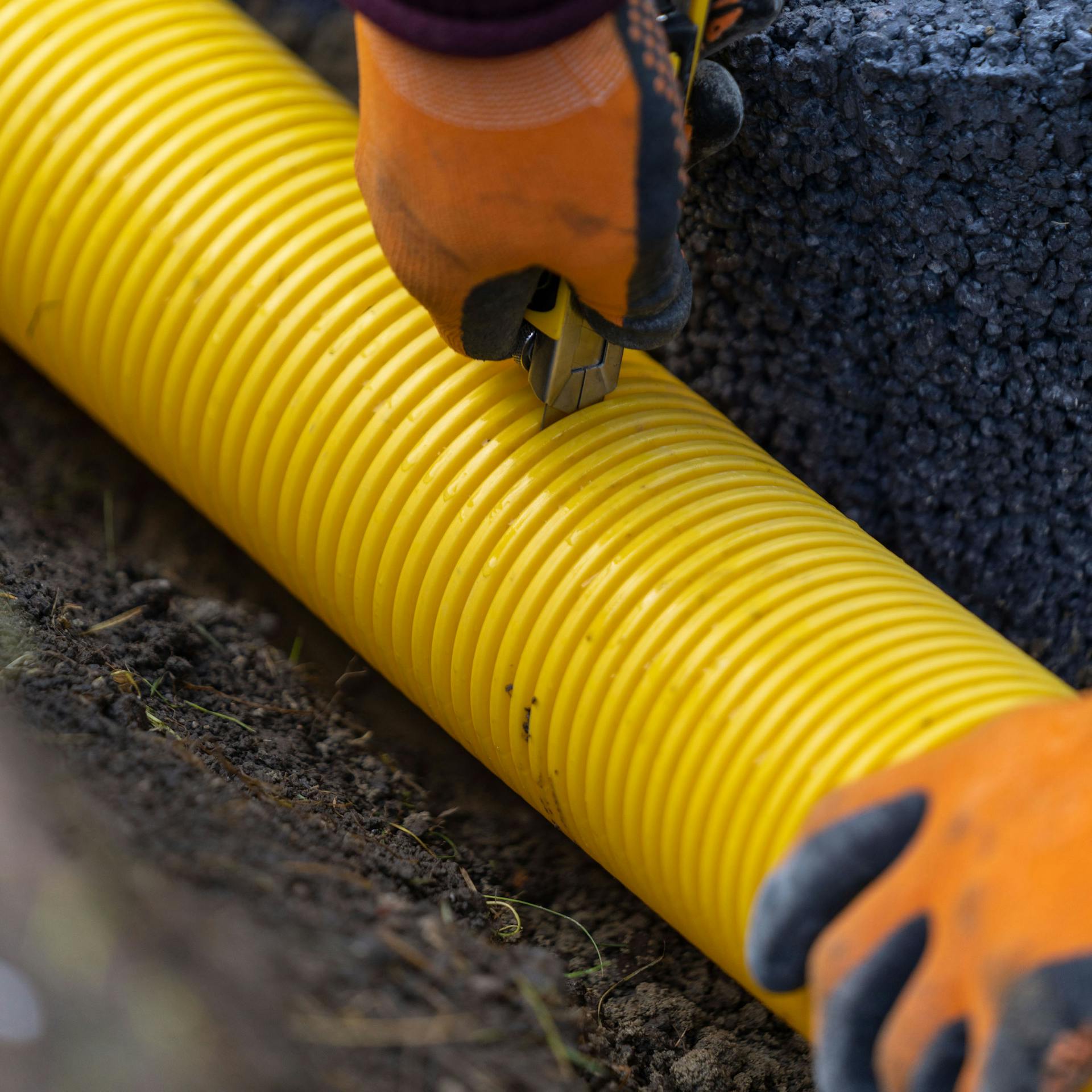 Person kürzt Drainagerohr.