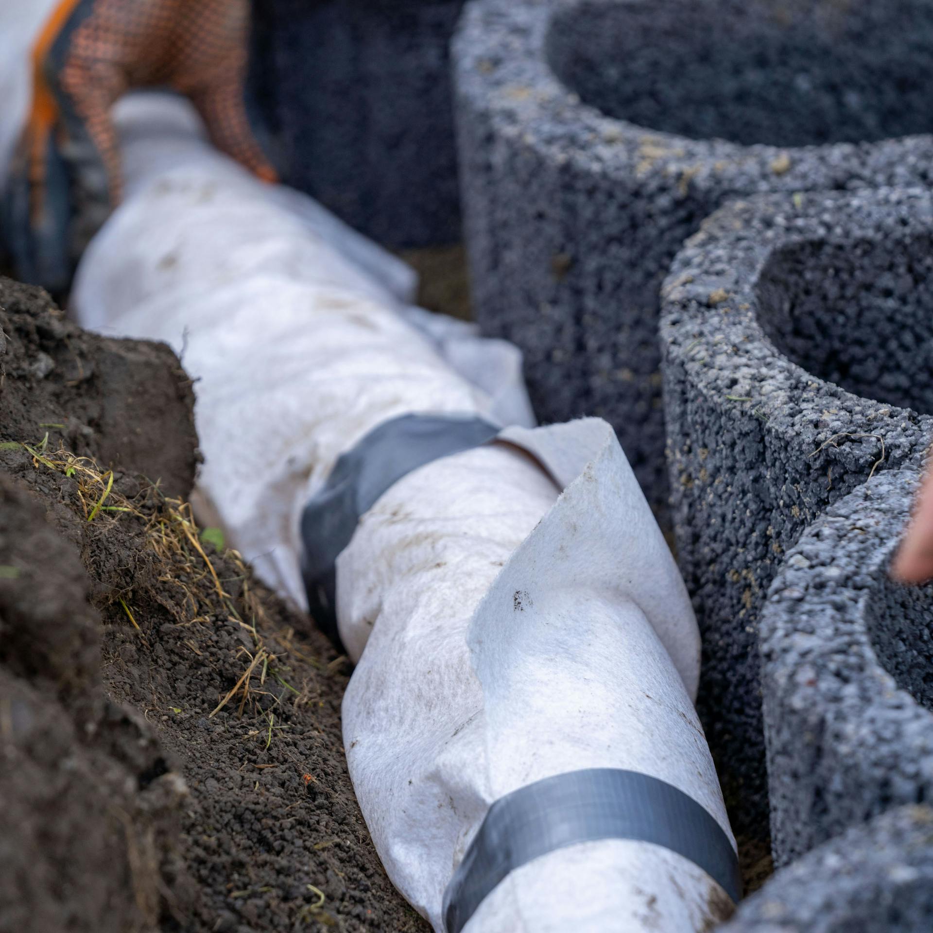 Ein Drainagerohr liegt hinter Pflanzkörben.