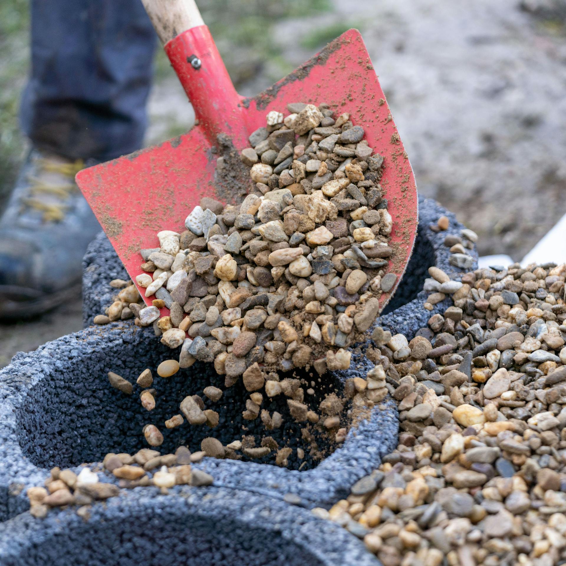Jemand füllt Kies in die Pflanzsteine.