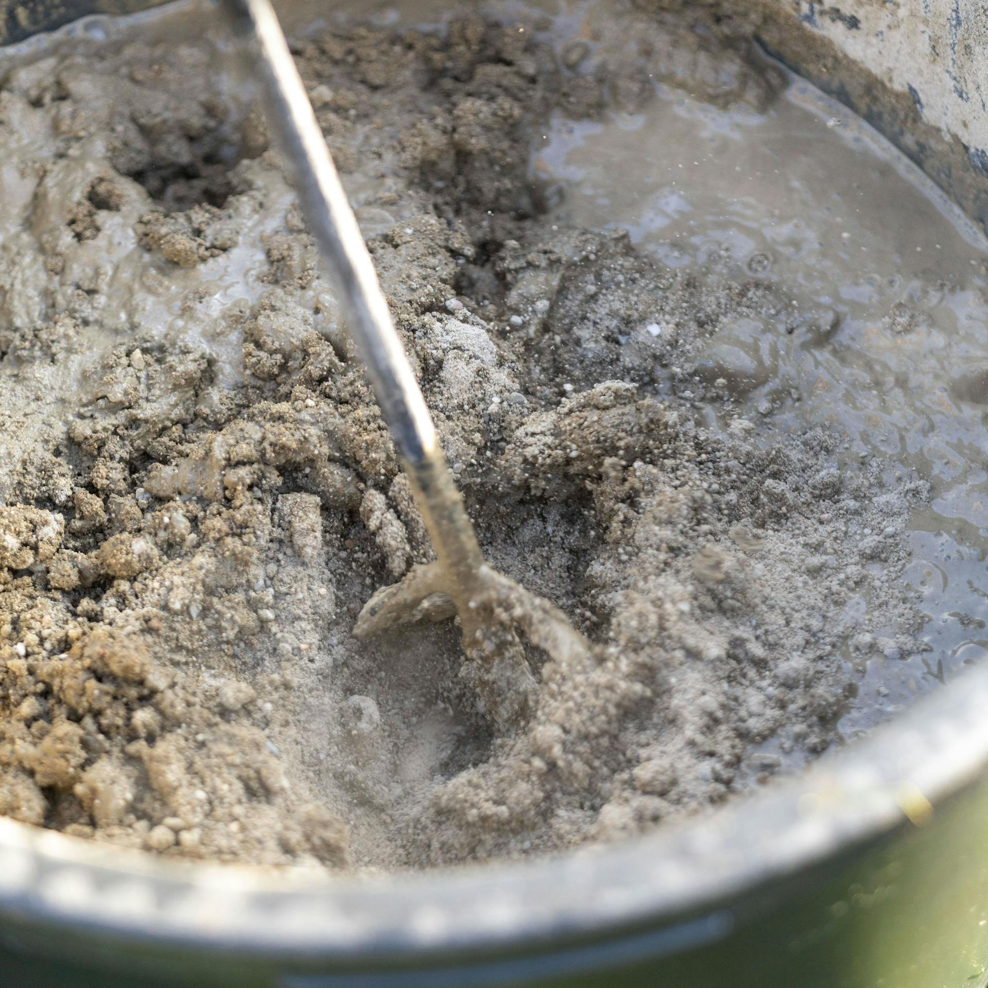 Mörtel wird mit Rührwerk in einem Eimer verrührt.