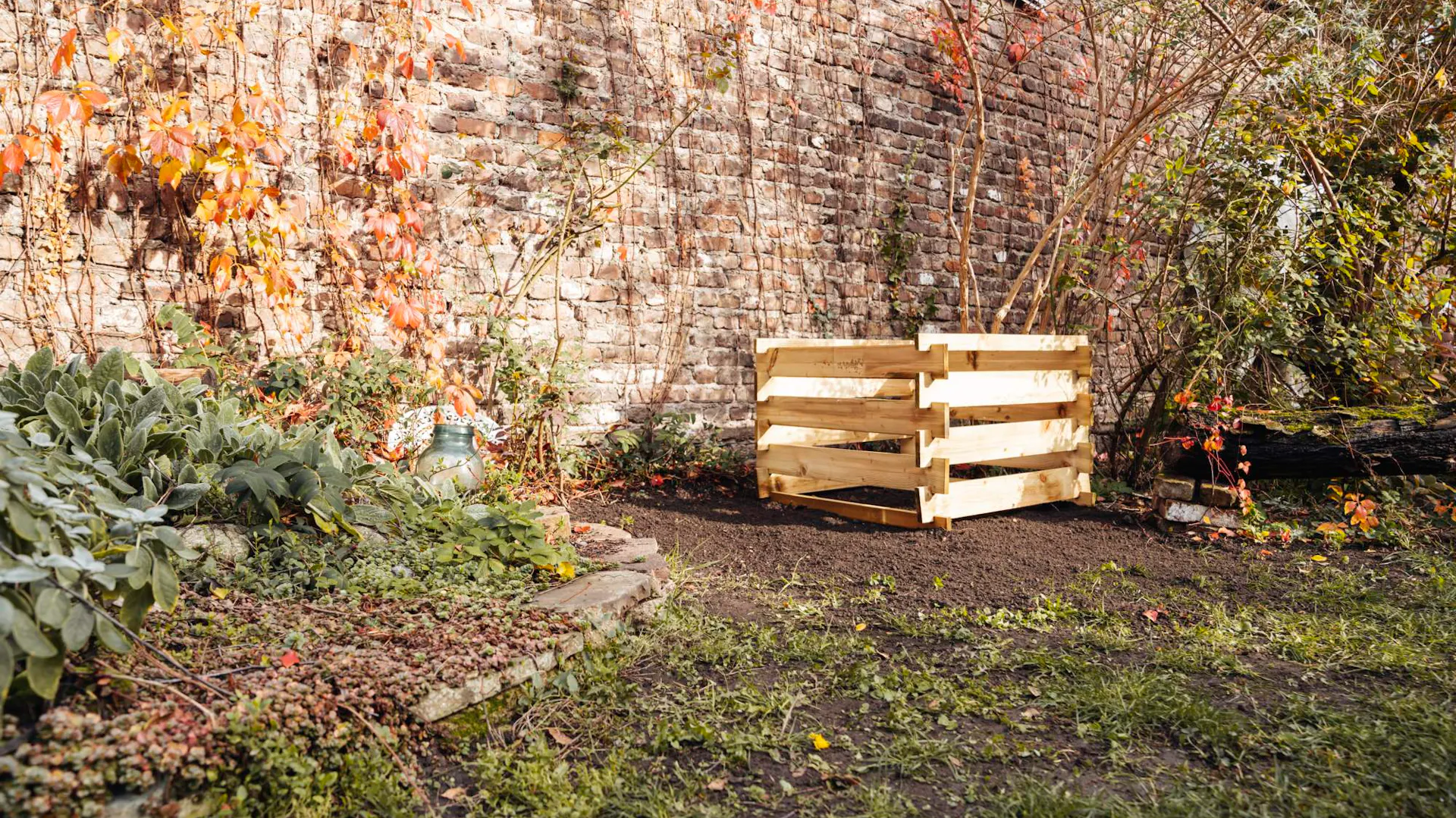 Compostiera vuota davanti al muro in un giardino autunnale