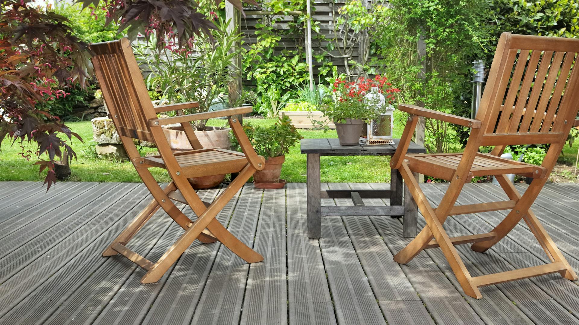 Auf einer Holzterrasse stehen Holzgartenmöbel.