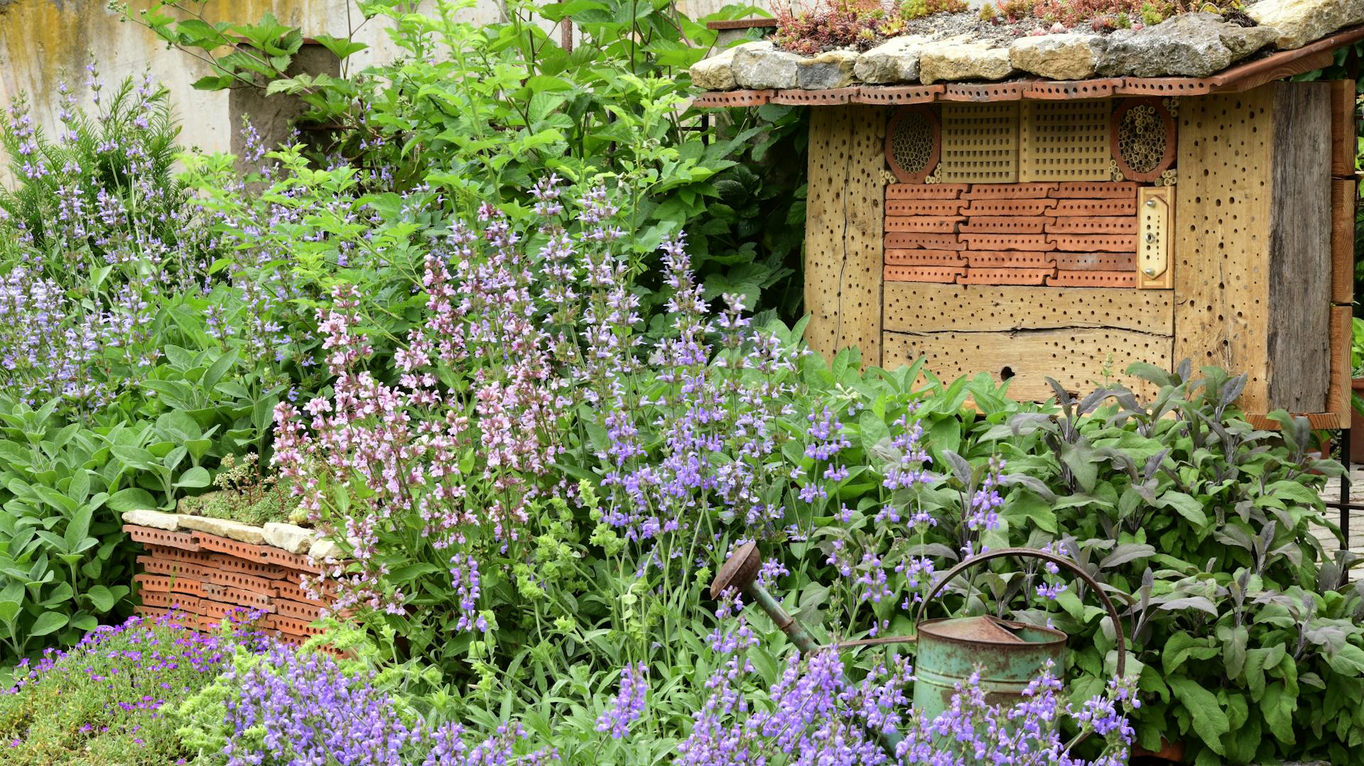 Ein großes Insektenhotel im Garten inmitten vieler Pflanzen