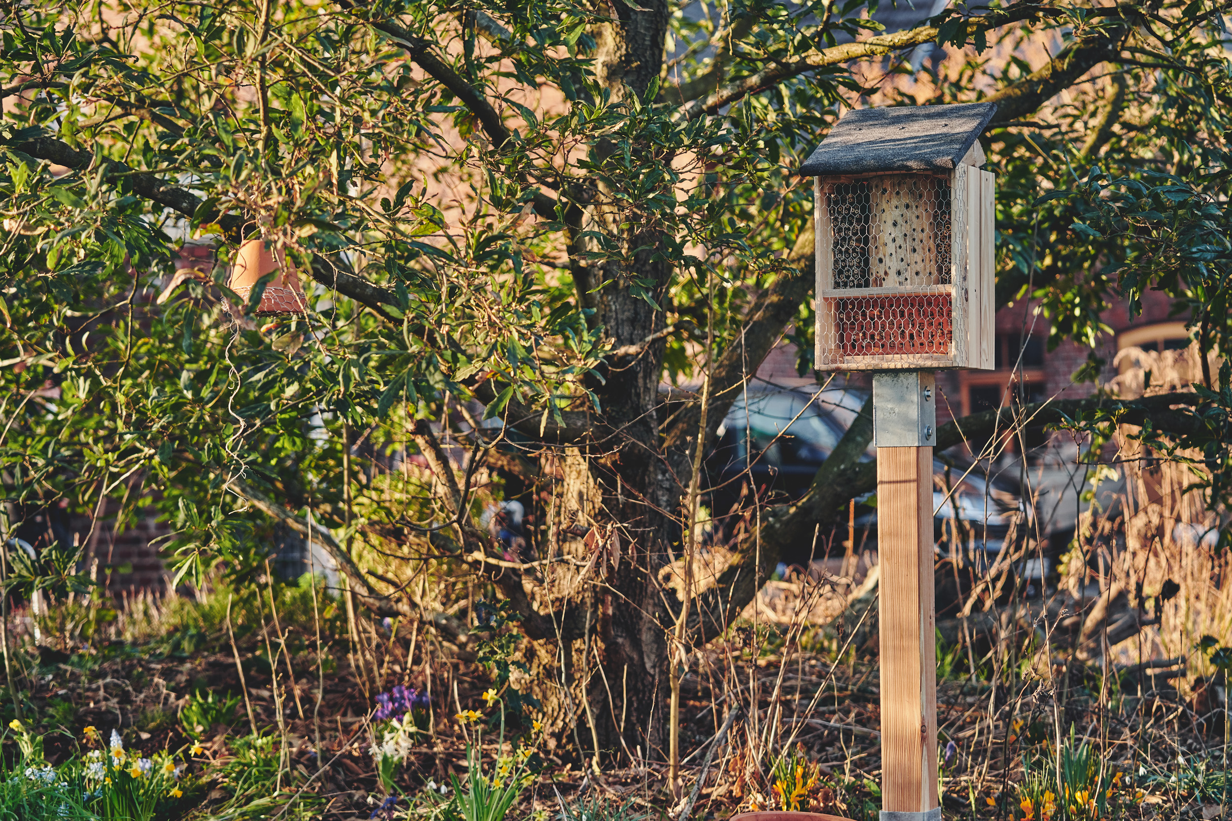 Ein fertiges Insektenhotel steht in naturnahem Garten.