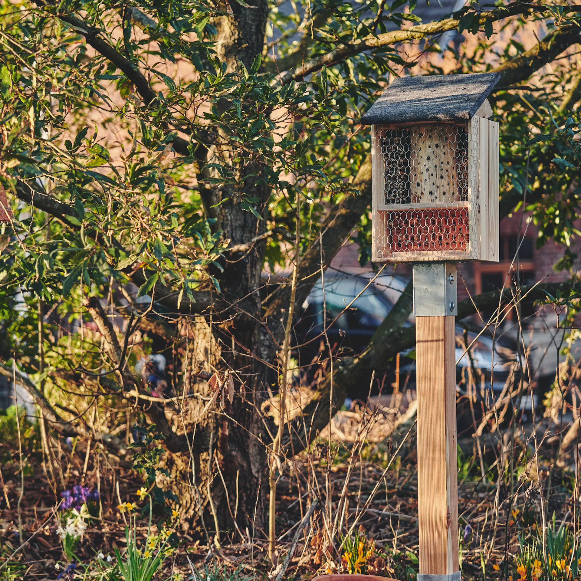 Ein fertiges Insektenhotel steht in naturnahem Garten.