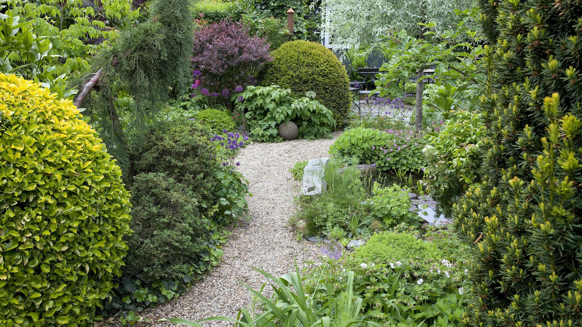 Kiesweg durch dicht bewachsenen Garten