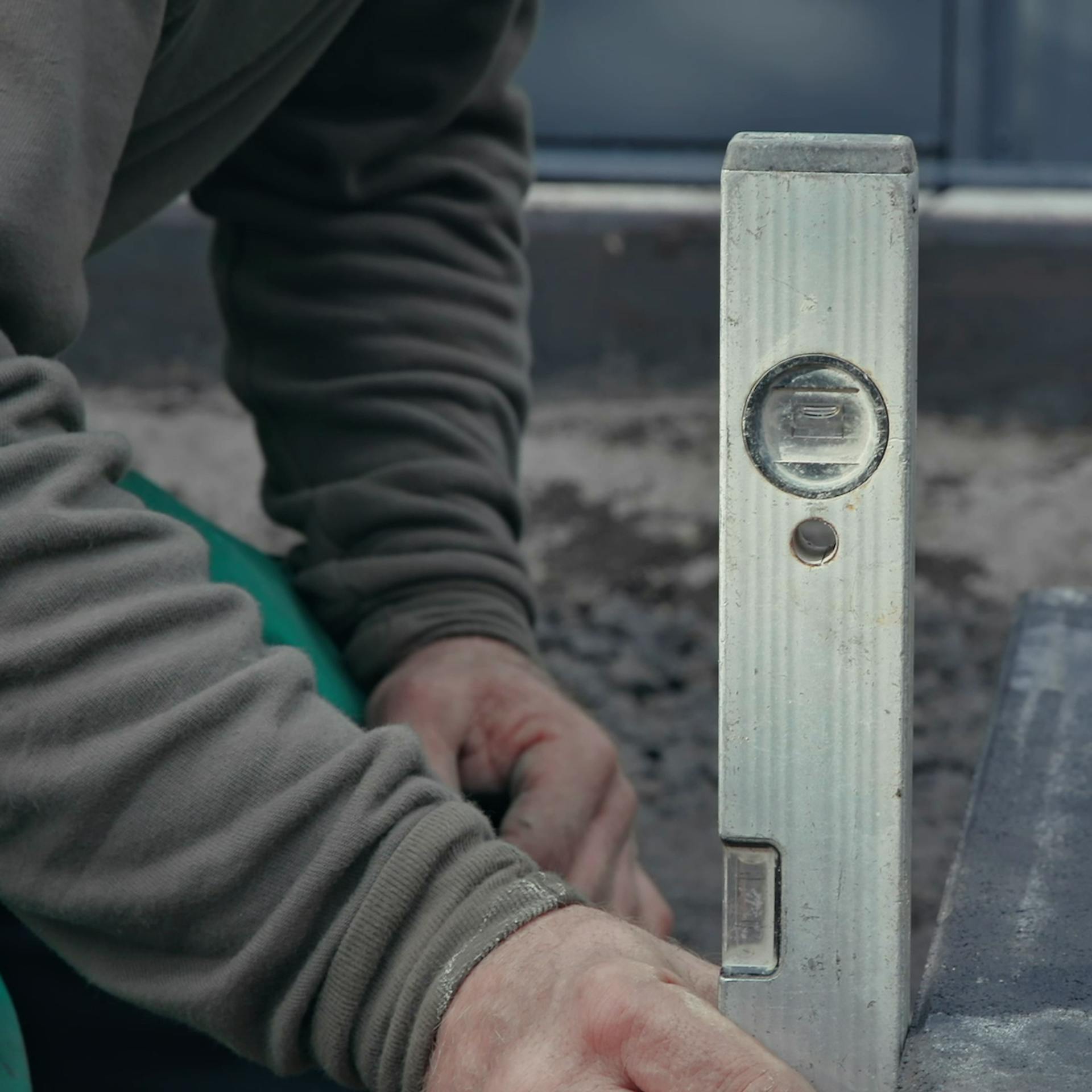 Heimwerker prüft korrekte Ausrichtung des Kantsteins mit Wasserwaage.