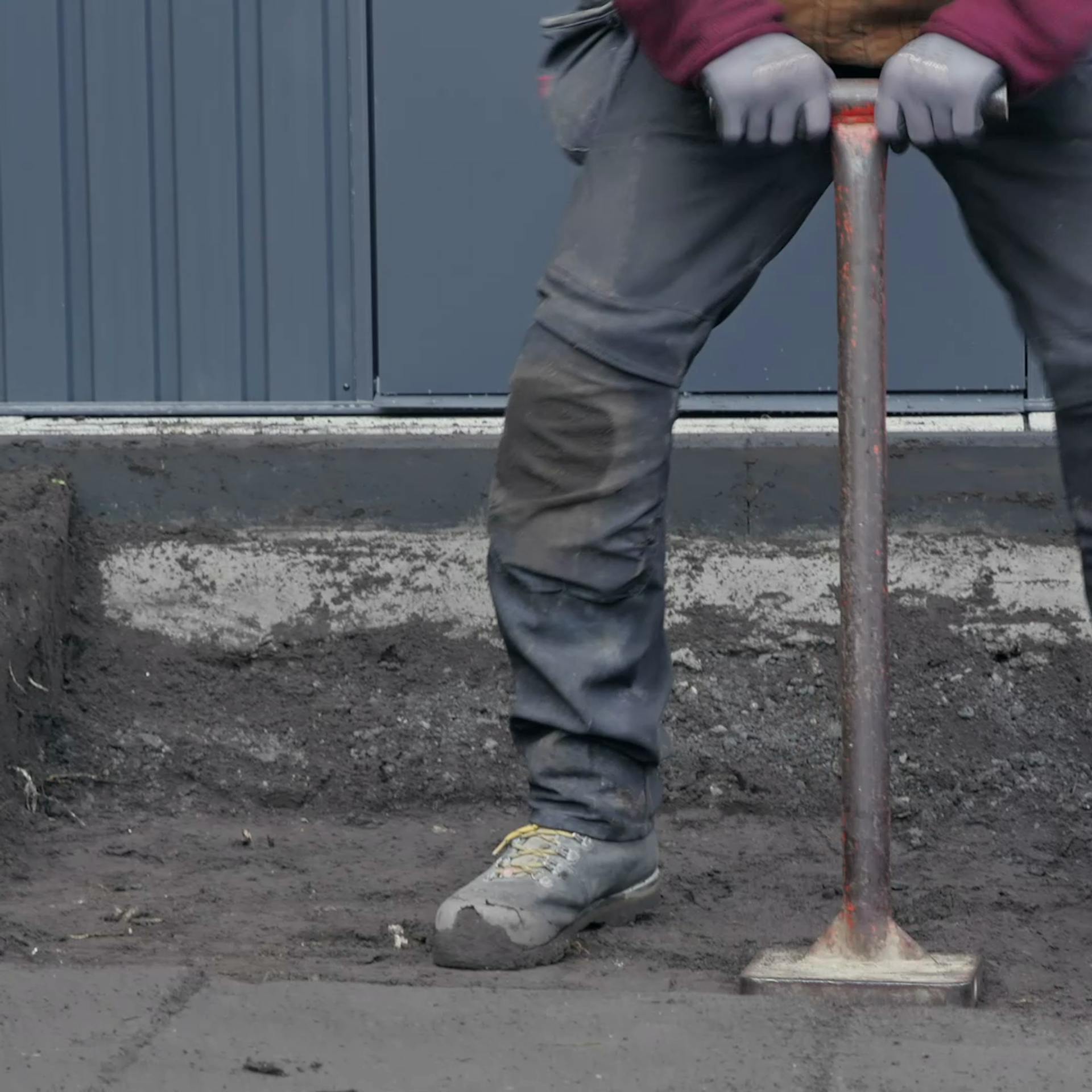 Heimwerker verdichtet ausgehobenen Boden mit Handstampfer.