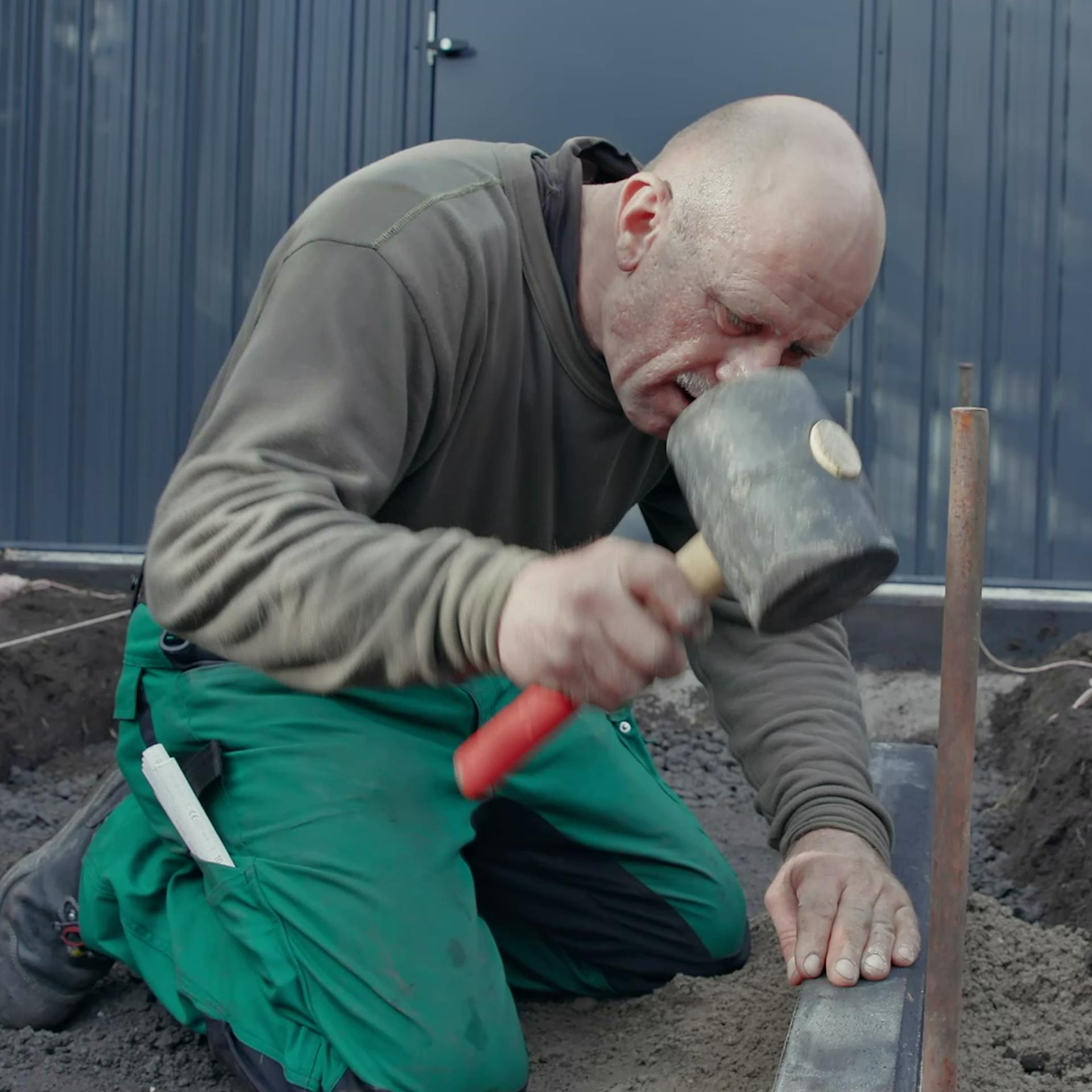 Person schlägt eingesetzten Kantstein mit Gummihammer in richtige Position.
