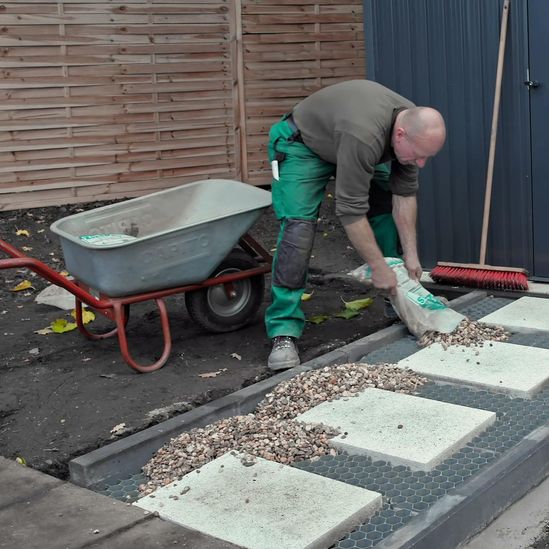Heimwerker füllt Zierkies in Fläche mit Kieswaben und Trittplatten ein.