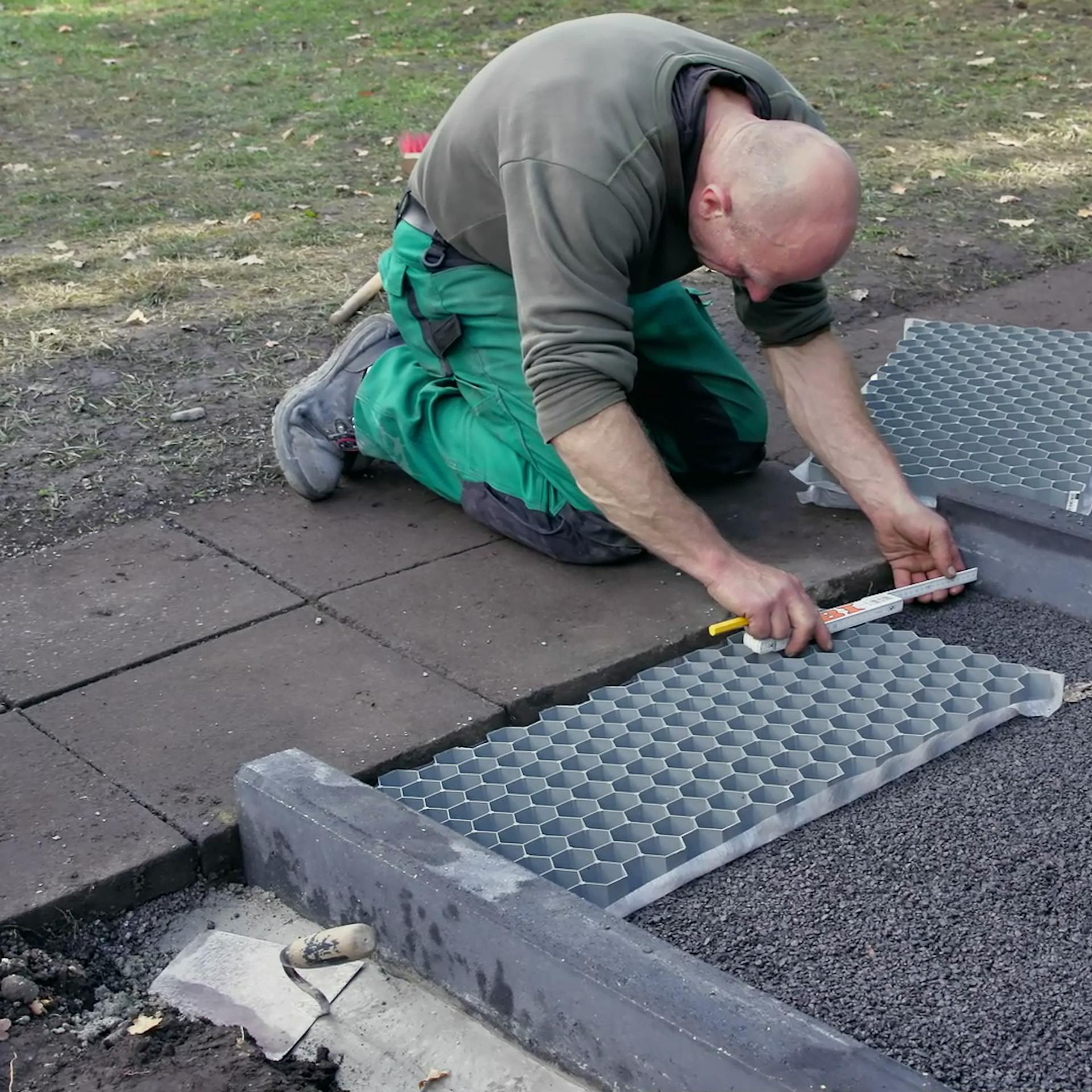 Heimwerker setzt Kieswaben mit richtiger Größe in Kiesweg ein.