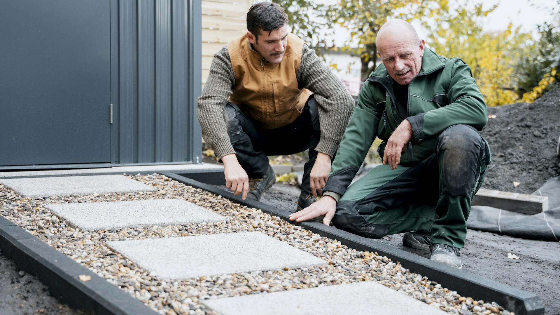 Kiesweg mit Kantsteinen und Trittplatten führt zu Gartenhaus.