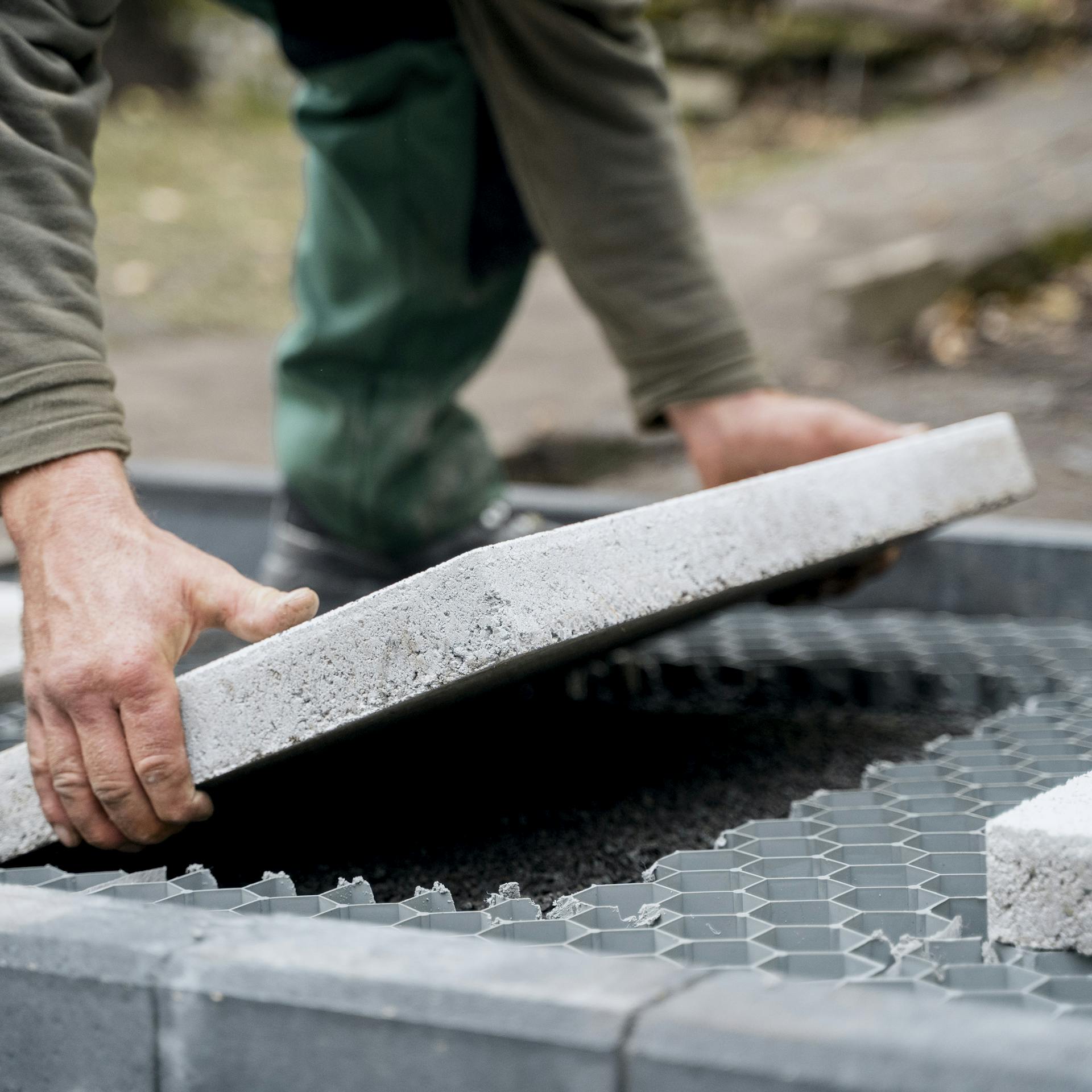 Eine Person legt eine Trittplatte in eine Aussparung zwischen Kieswaben.