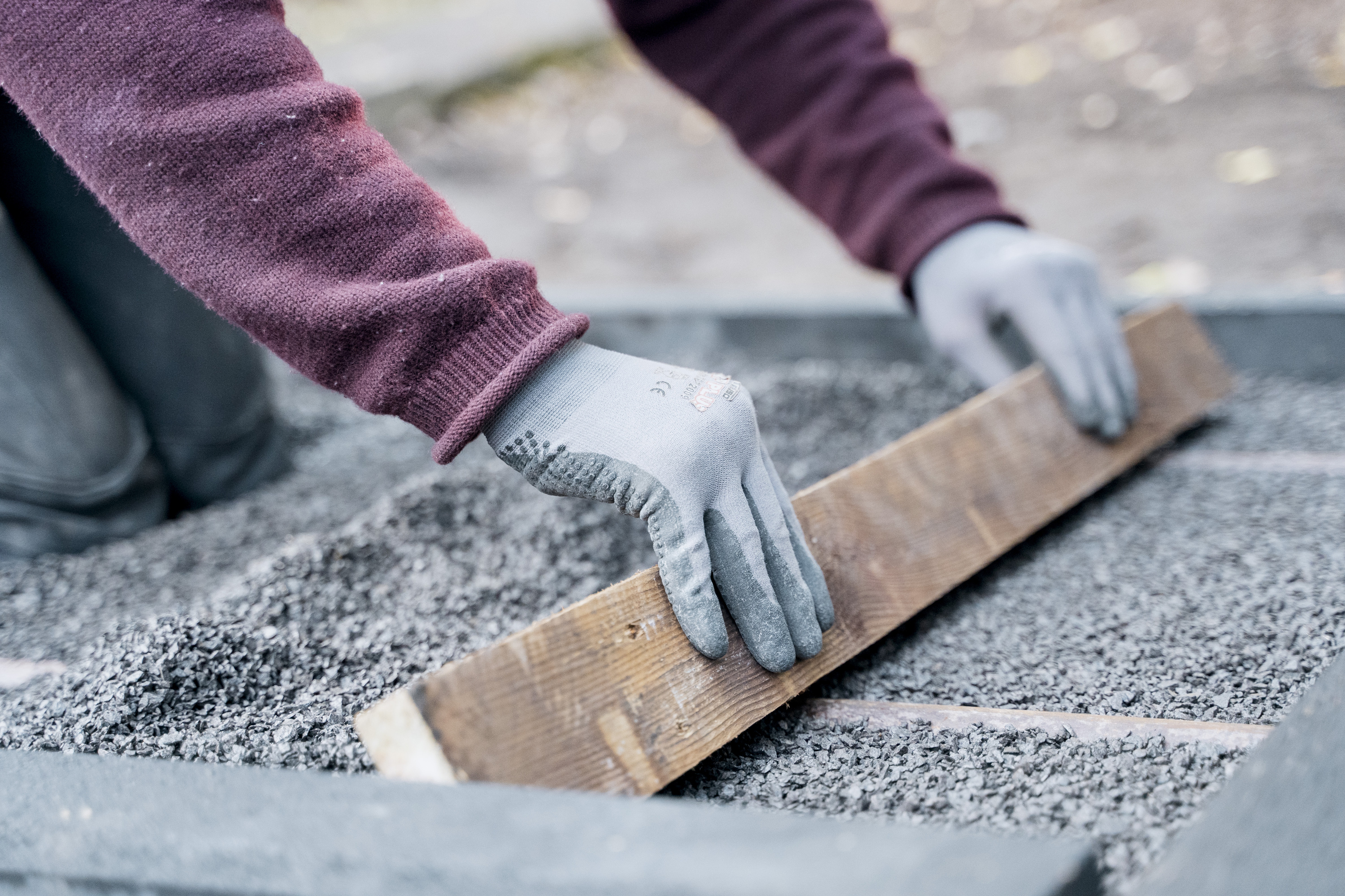 Valaki egy deszkával egyengeti a kavicsréteget.