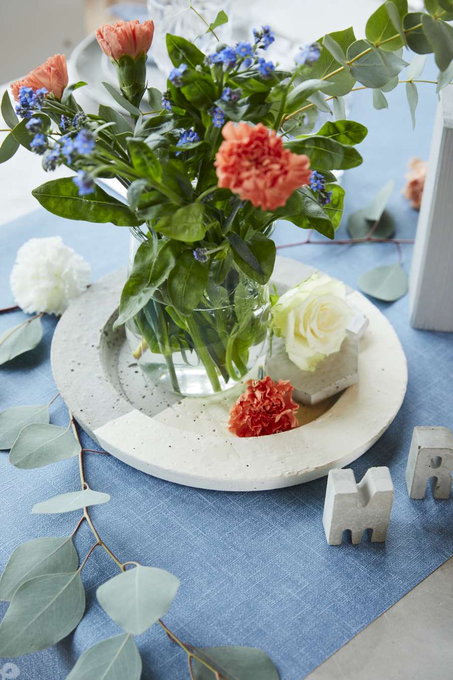 Ein Schmuckschale aus Beton, auf der eine Vase mit Blumen steht