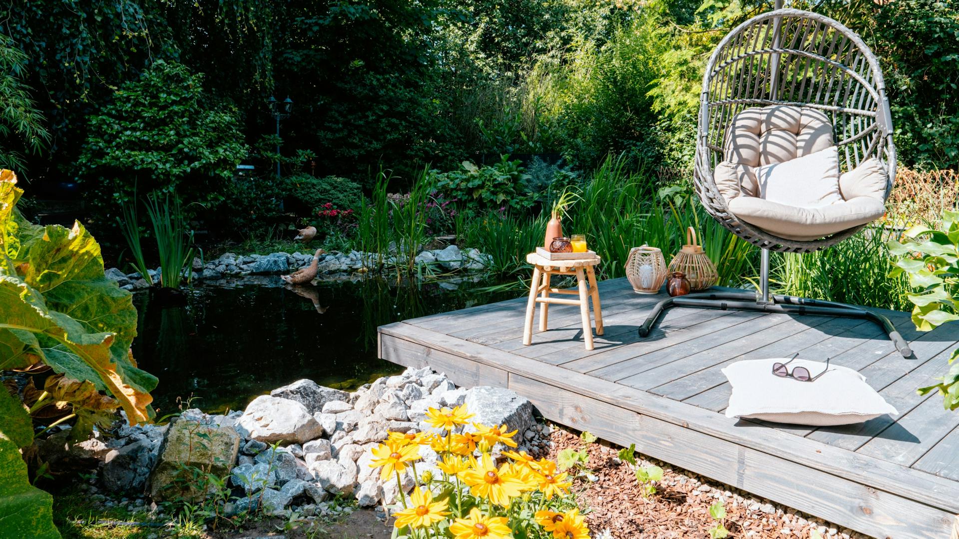 Steg mit Hängesessel vor einem Teich