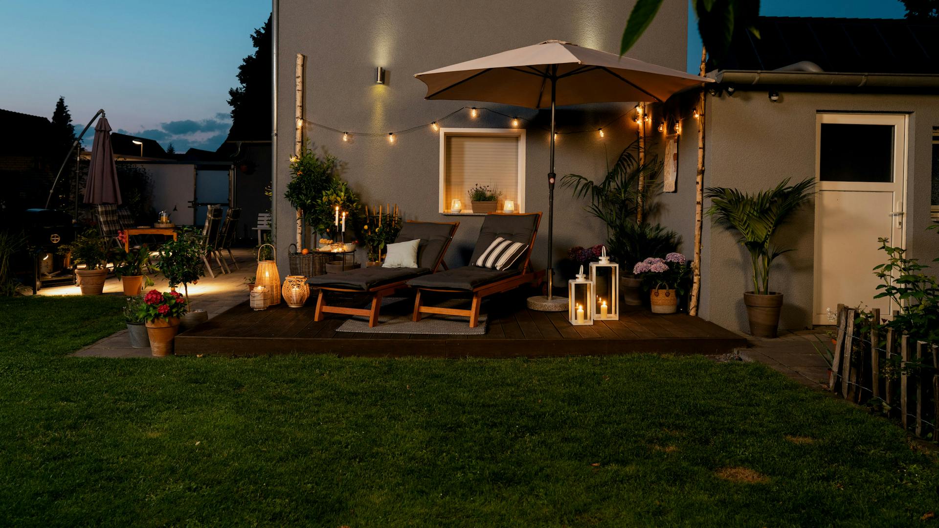 Beleuchtete Terrasse mit Sonnenliegen am Abend