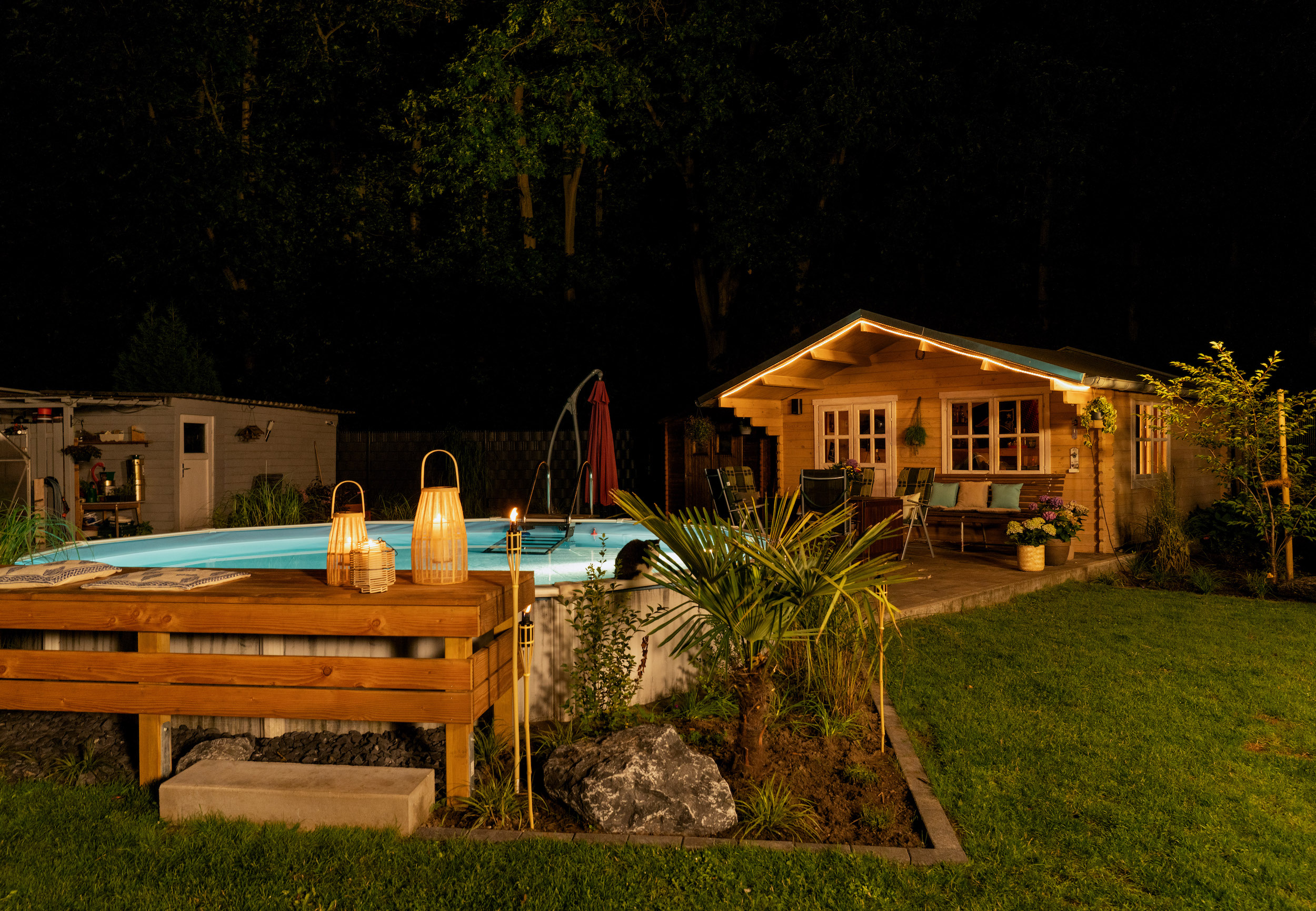 Beleuchteter Pool vor einem Gartenhaus