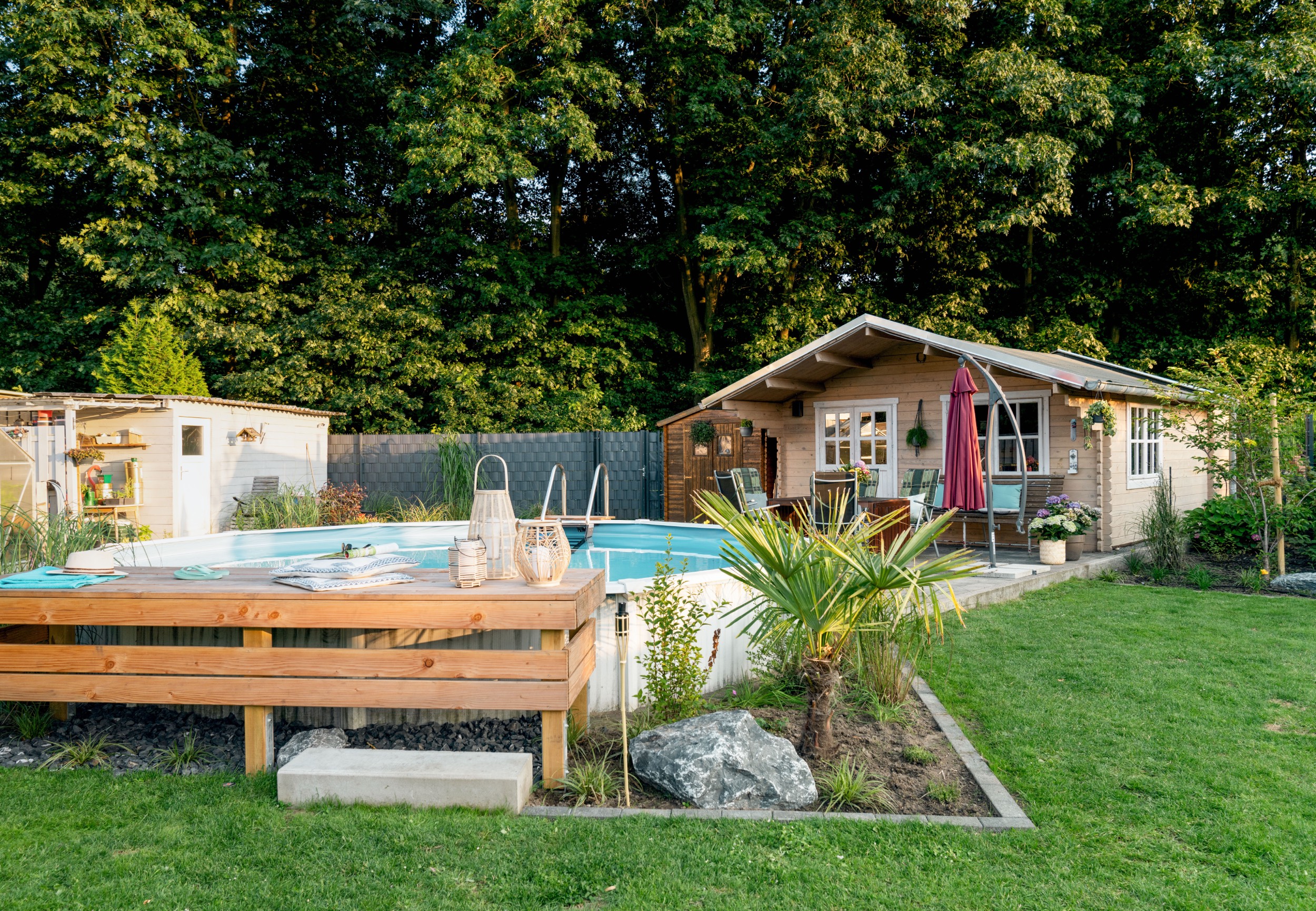 Verkleideter Pool mit Steg vor einem Gartenhaus