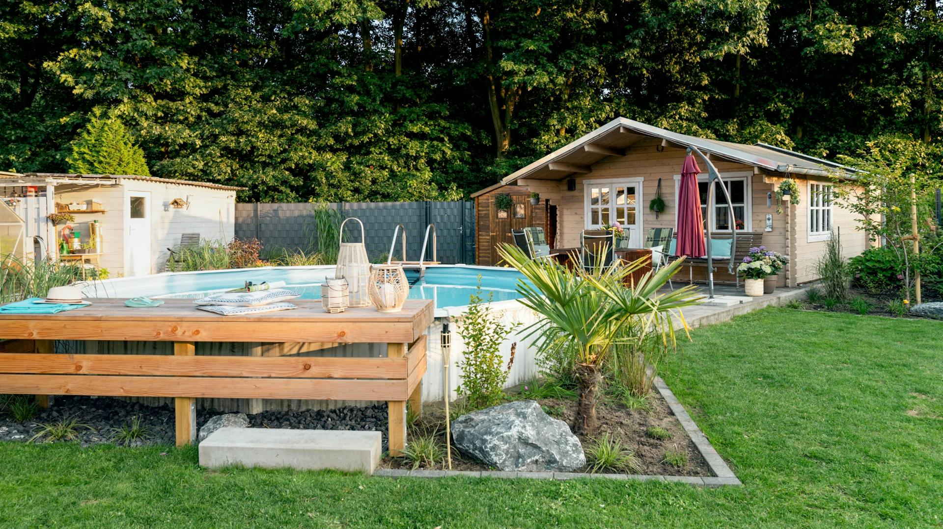 Verkleideter Pool mit Steg vor einem Gartenhaus