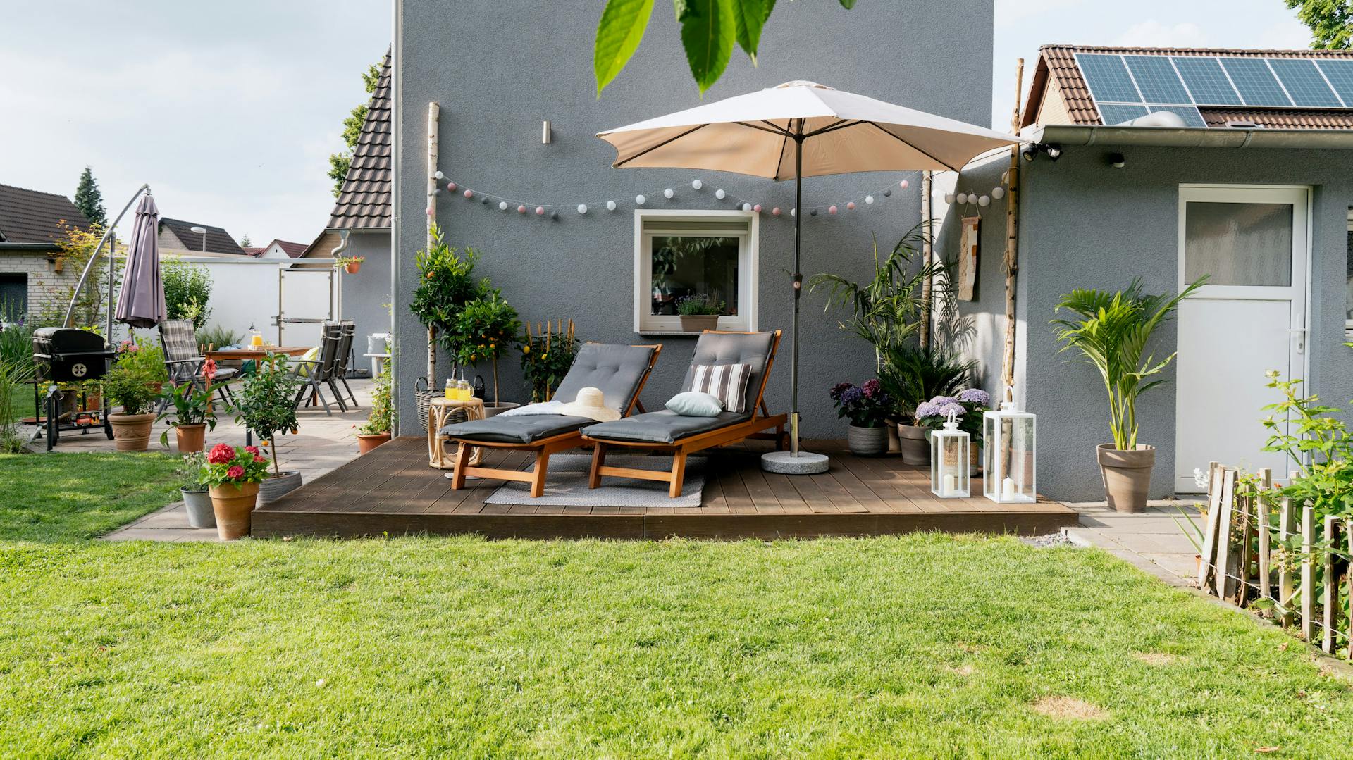 Terrasse vor Haus mit Sonnenliegen und Sonnenschirm