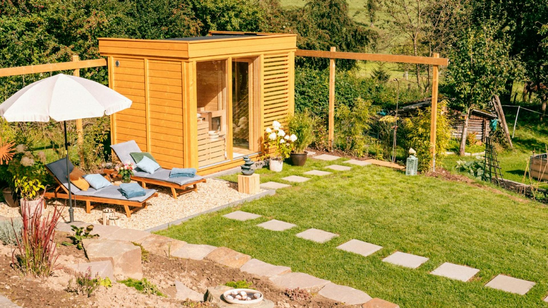 Gehwegplatten im Garten führen zu Saunahaus.