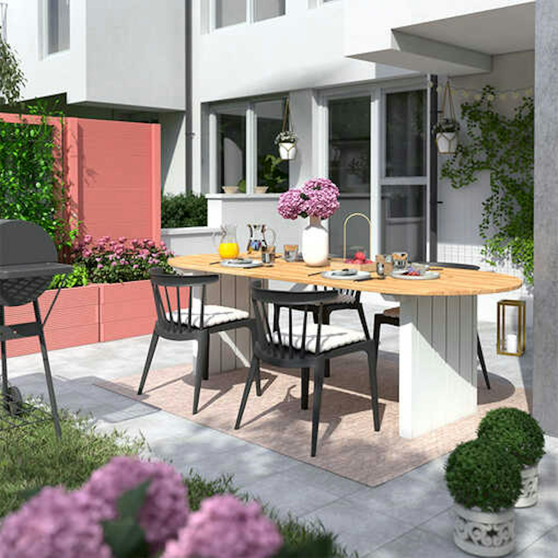 Gartentisch Emilia steht auf einer hellen Terrasse, wo das Hochbeet Alfred in einem pastellrot als Sichschutz aufgestellt worden ist