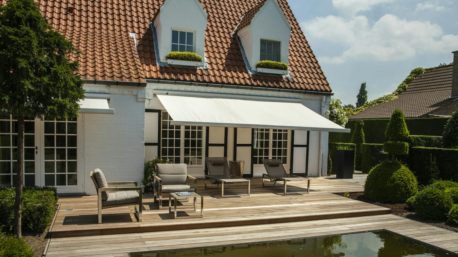 Eine helle Markise am Haus ist ausgefahren.