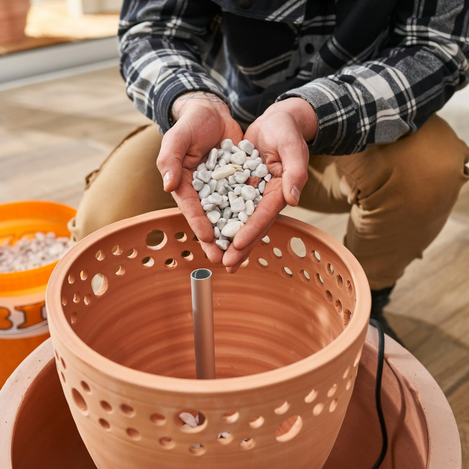 Zierkies wird mit der Hand in den Pflanztopf eingefüllt.