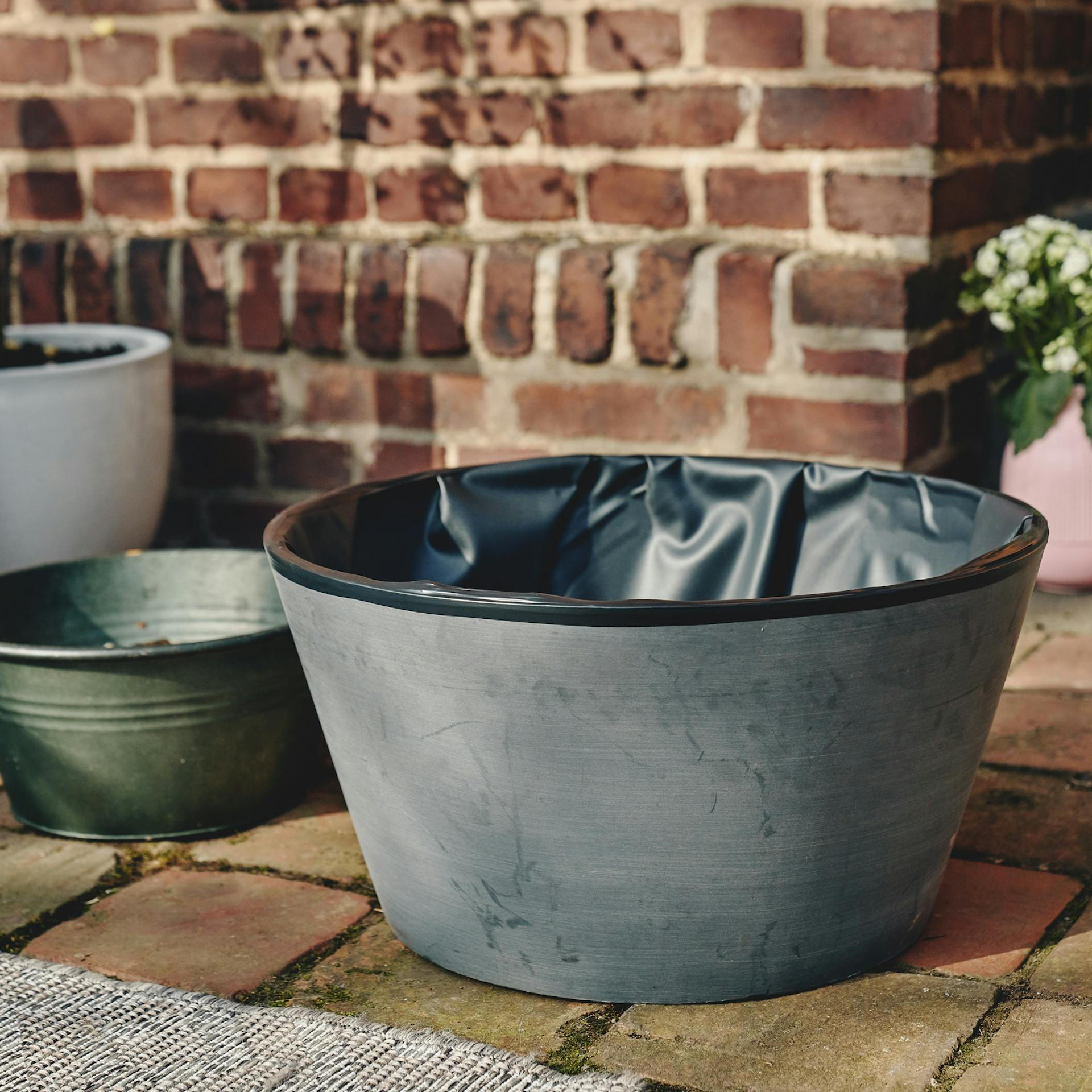 Miniteich mit Teichfolie ausgekleidet steht auf Terrasse.