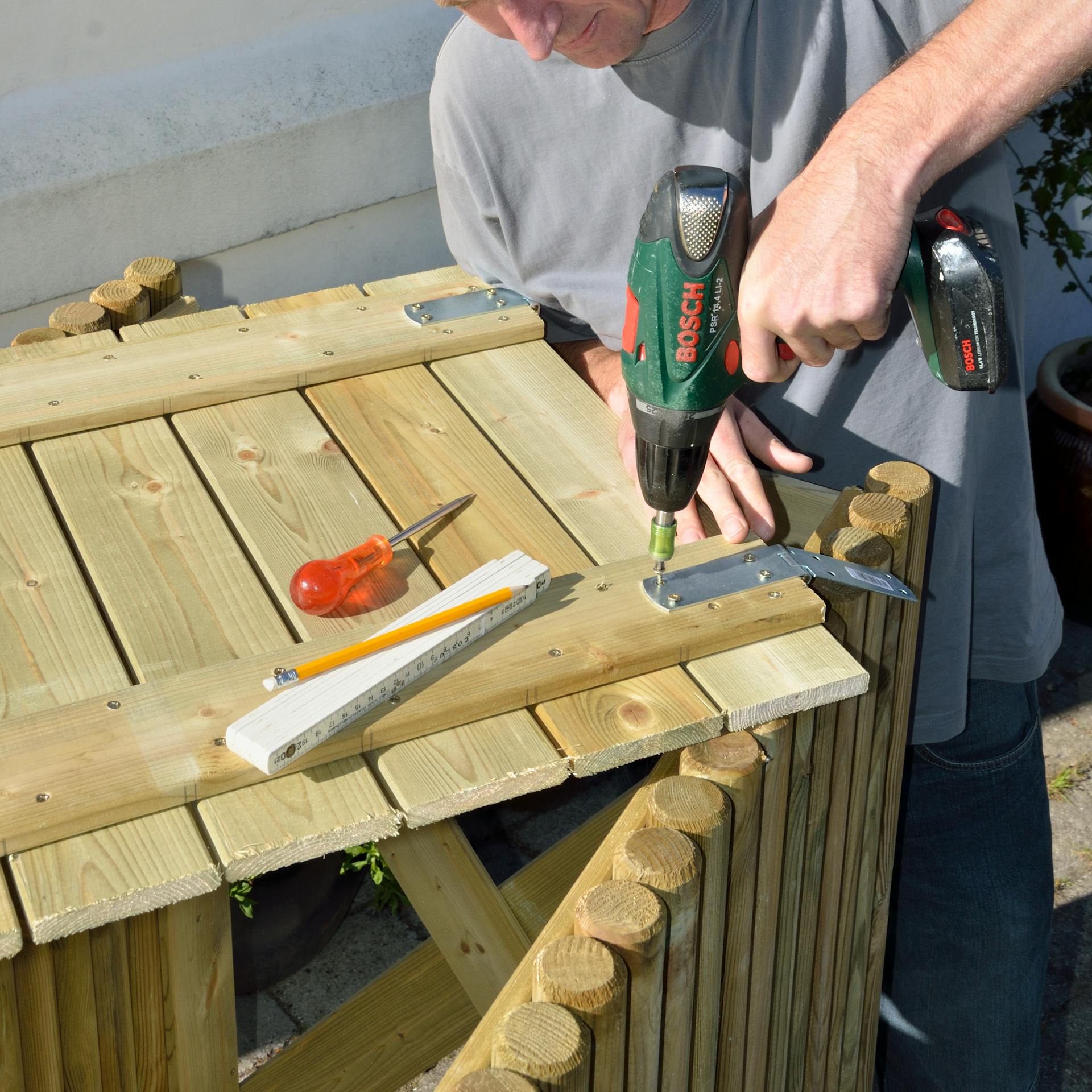 Osoba skrutkuje závesy na box na smetnú nádobu