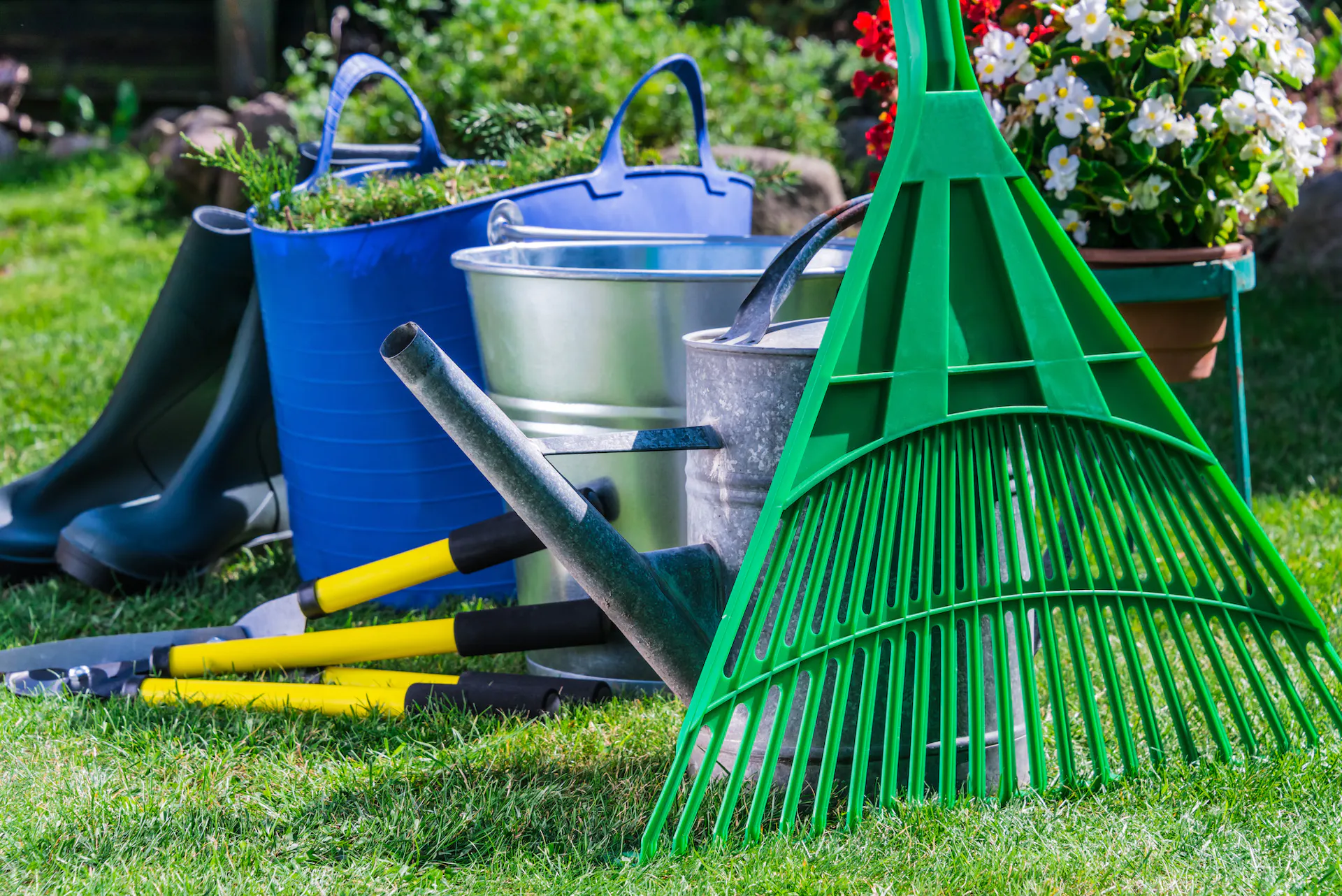 Râteau, outils de jardin, seau et bottes en caoutchouc dans le jardin