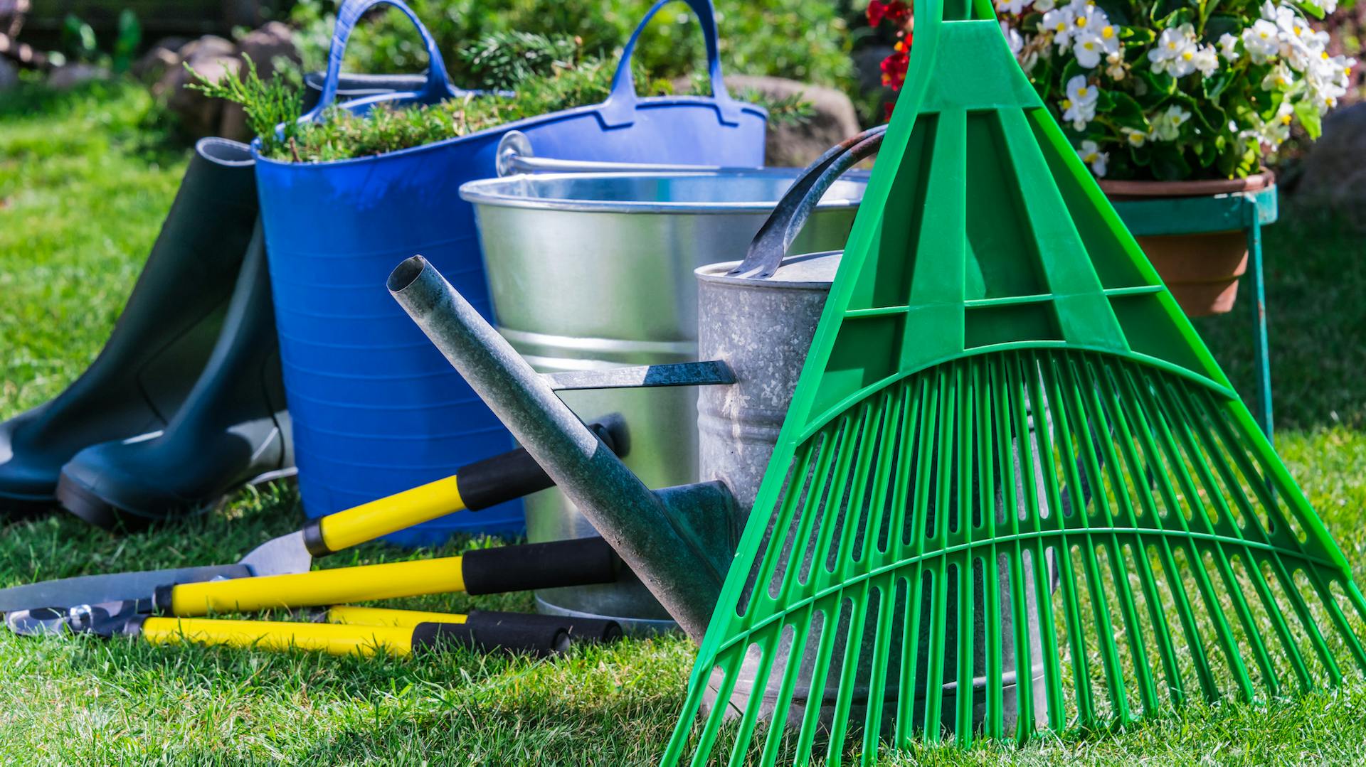 Rastrello, attrezzi da giardino, secchio e stivali di gomma in giardino
