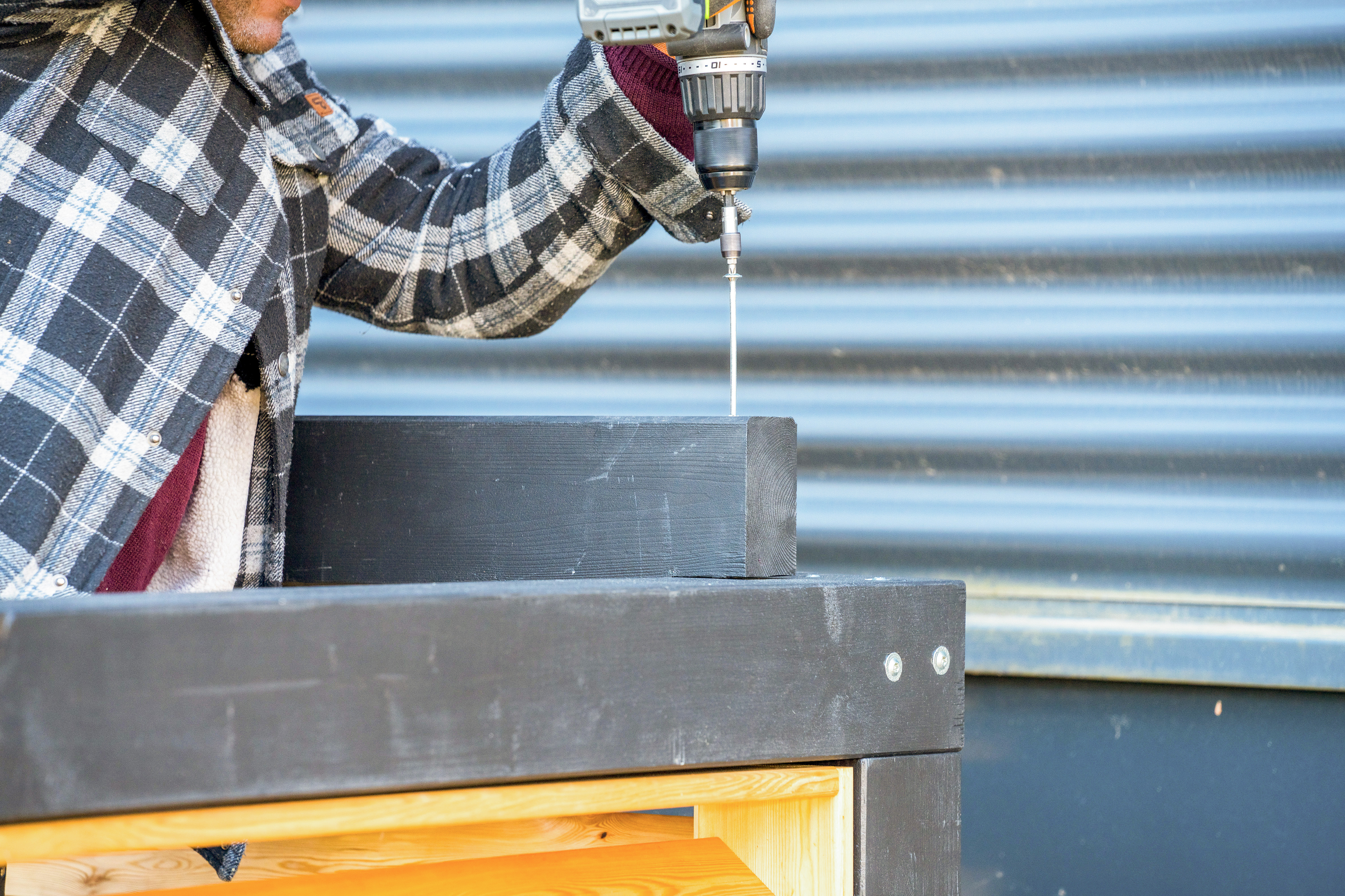 Heimwerker schraubt Balken auf dem Dach fest