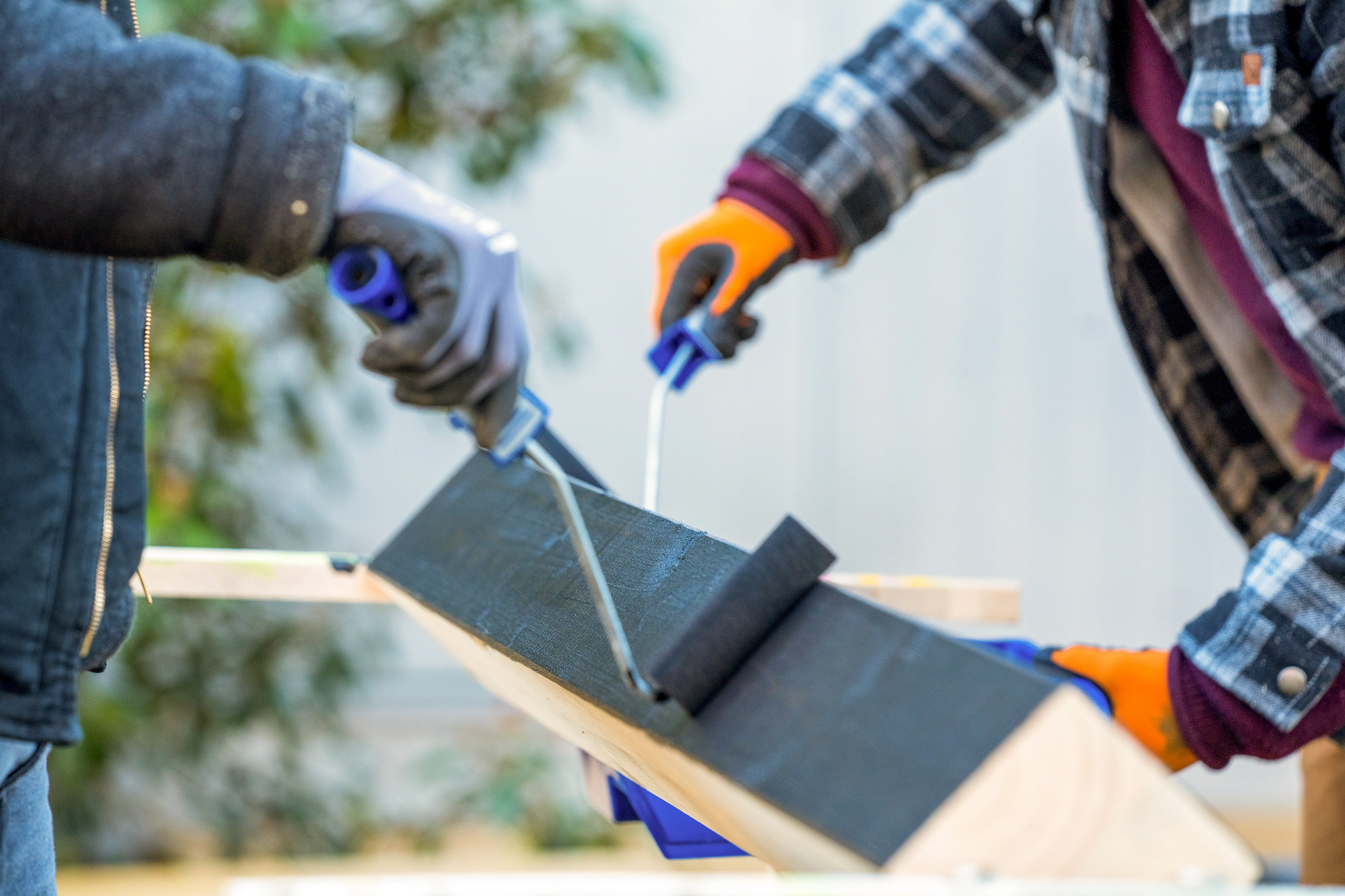 Zwei Heimwerker lackieren Balken mit Farbrollen