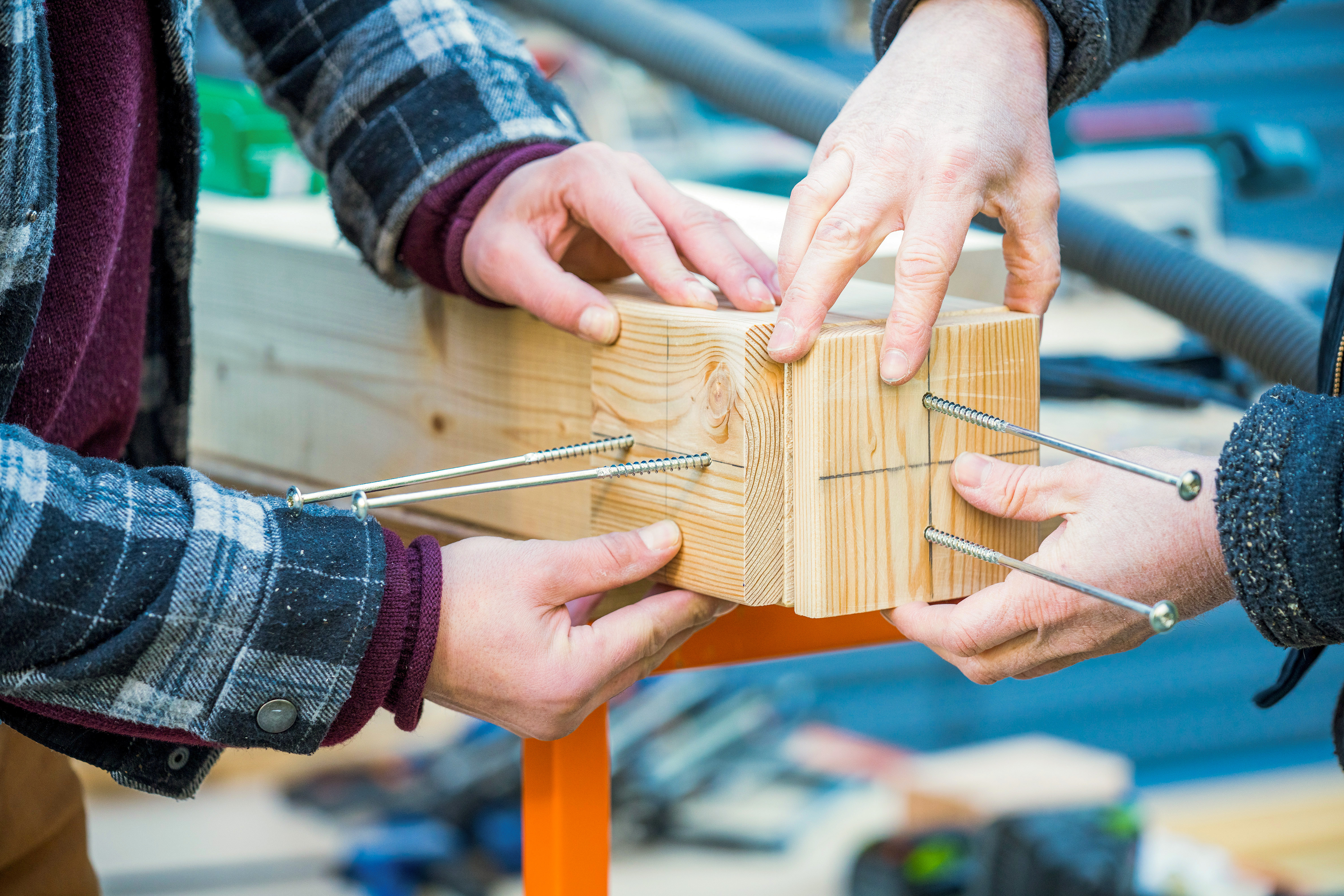 Heimwerker halten Schablonen an, um die Balken zu verschrauben
