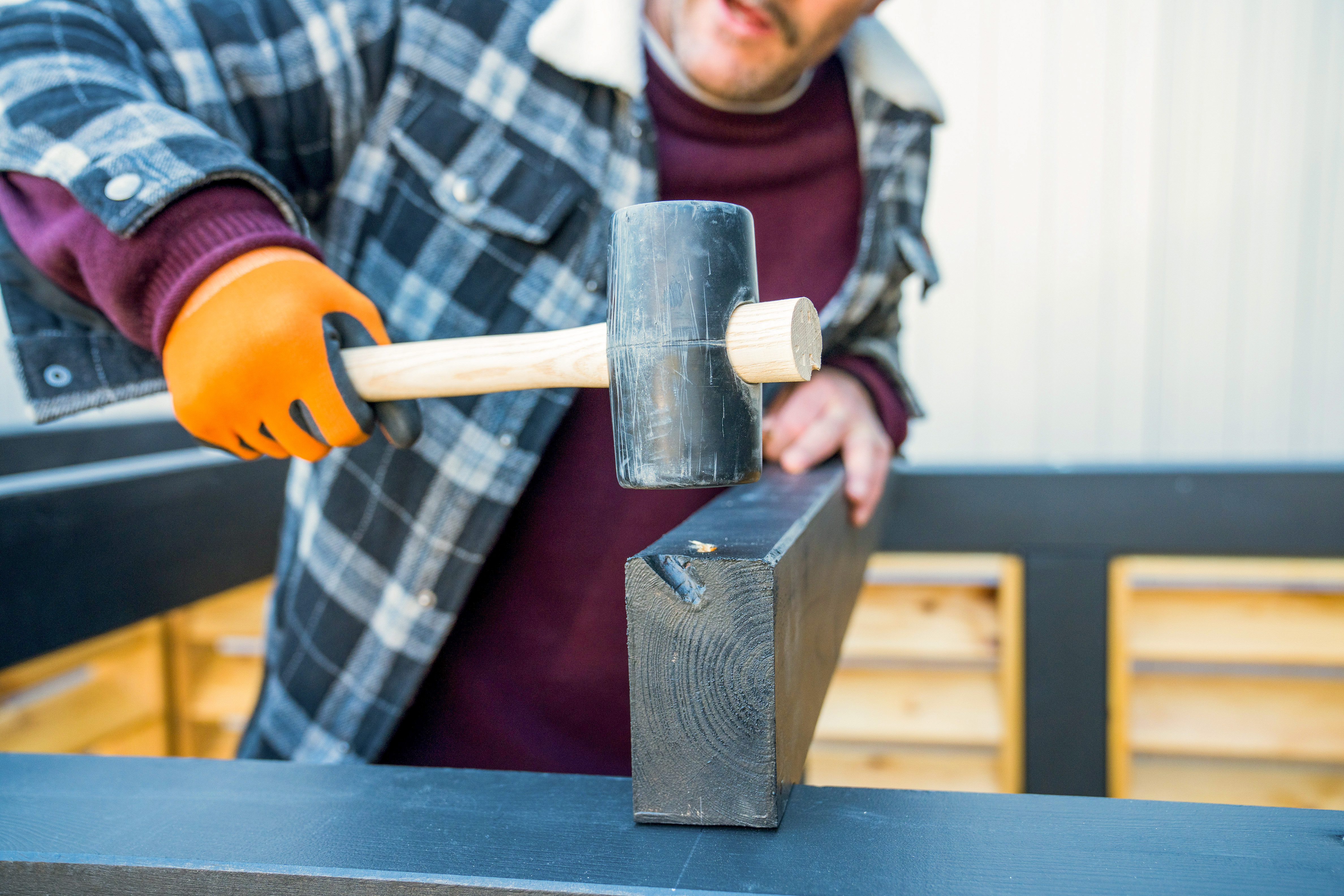 Heimwerker klopft Dachsparren mit einem Gummihammer fest