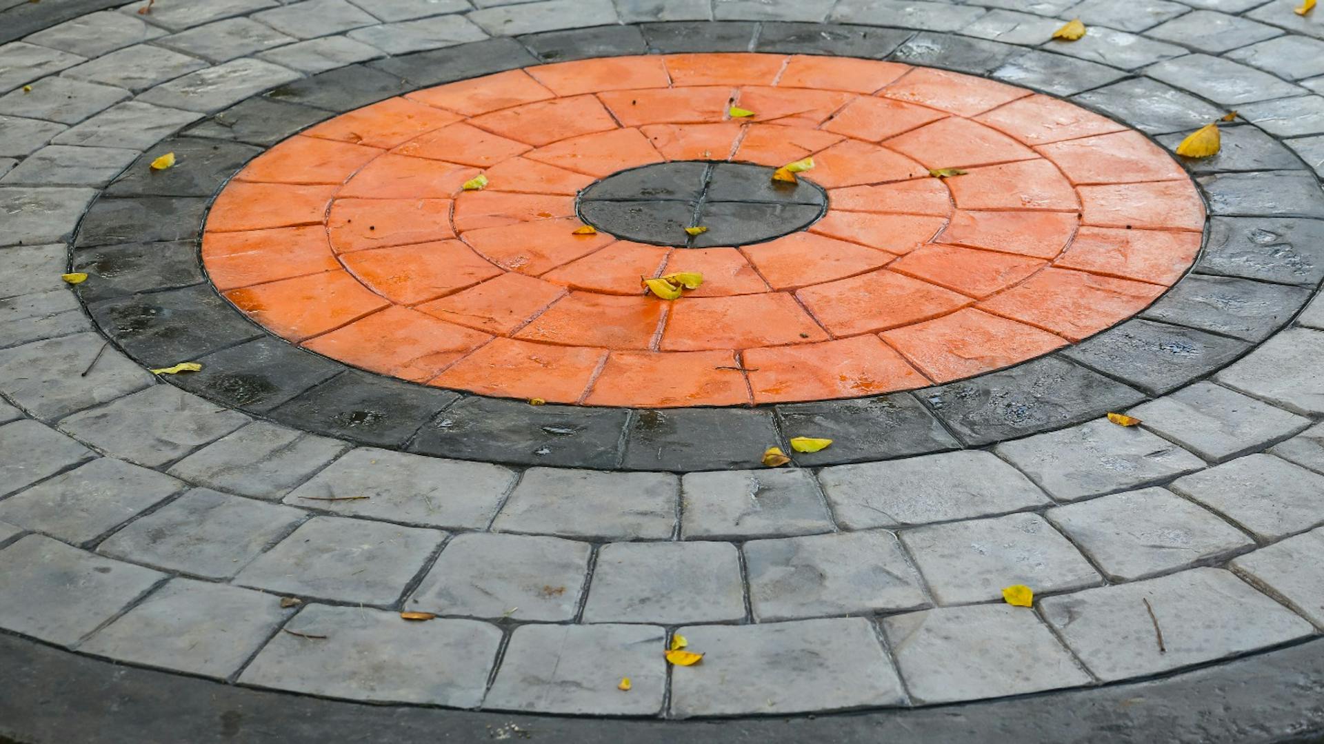 Körbe lerakott, festett térkövek szürke, fekete és narancssárga színben.