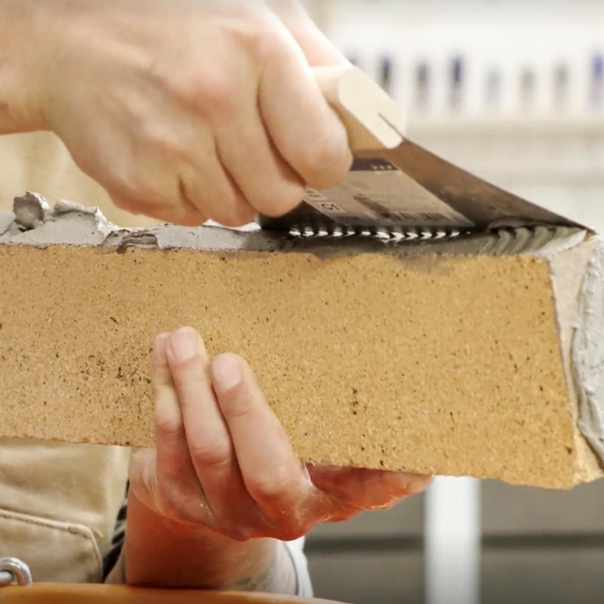 Odstranění přebytečné malty z cihly zubovou stěrkou.