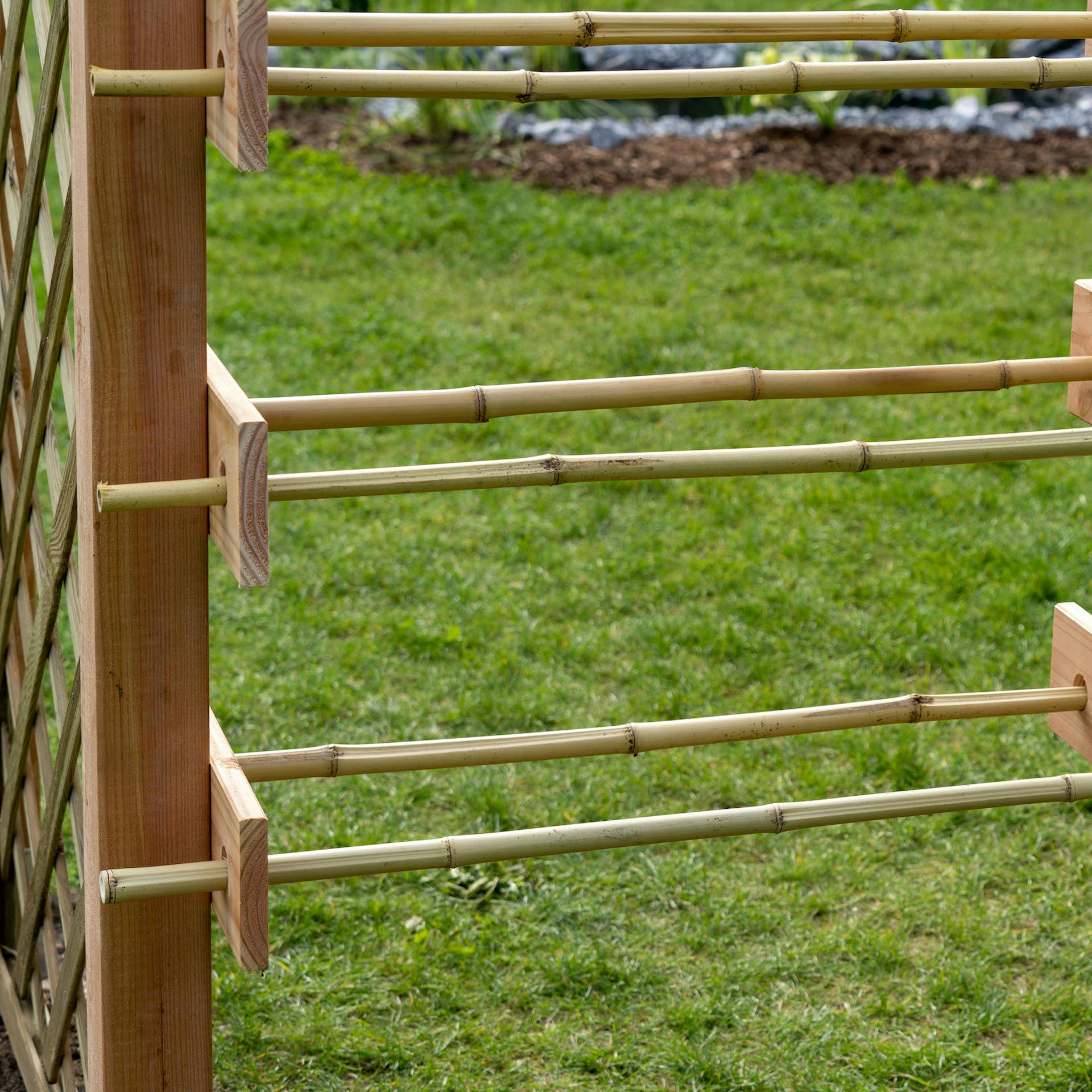 Két bambuszrúd van beszúrva egy deszkába jobbra és balra.