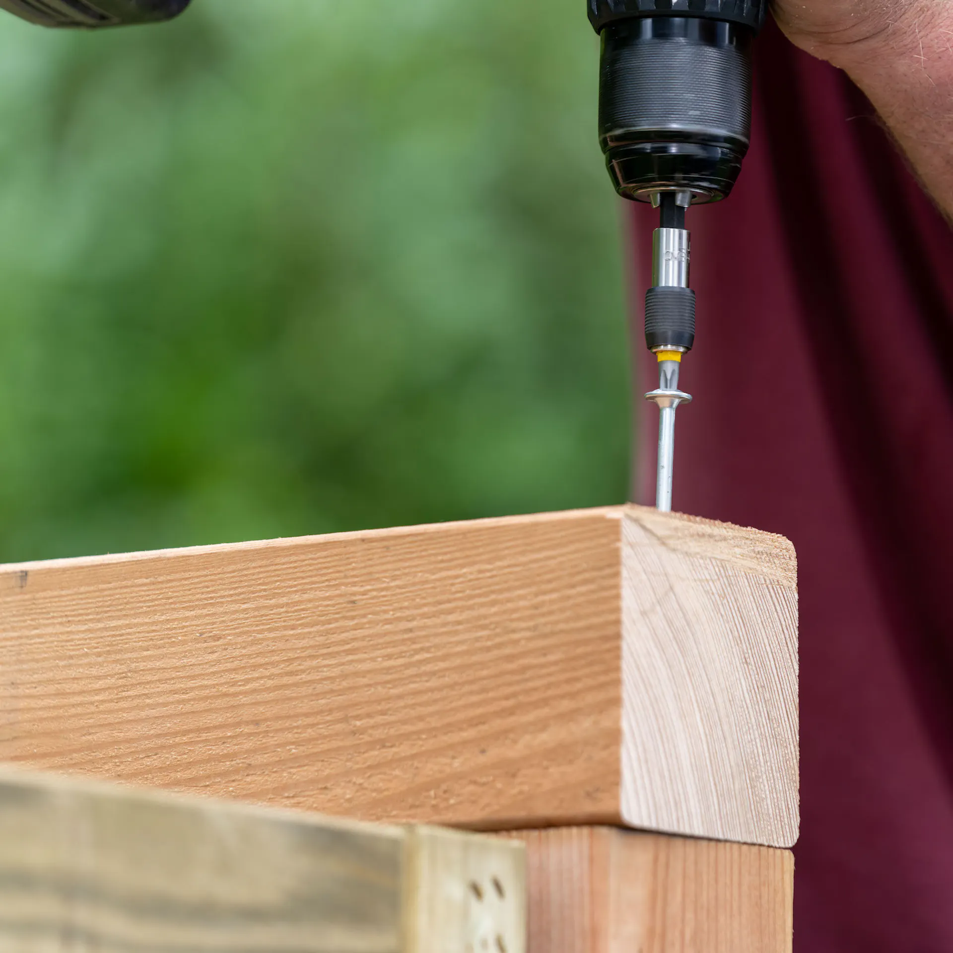 Egy barkácsoló csavart csavaroz be a faszerkezetbe.