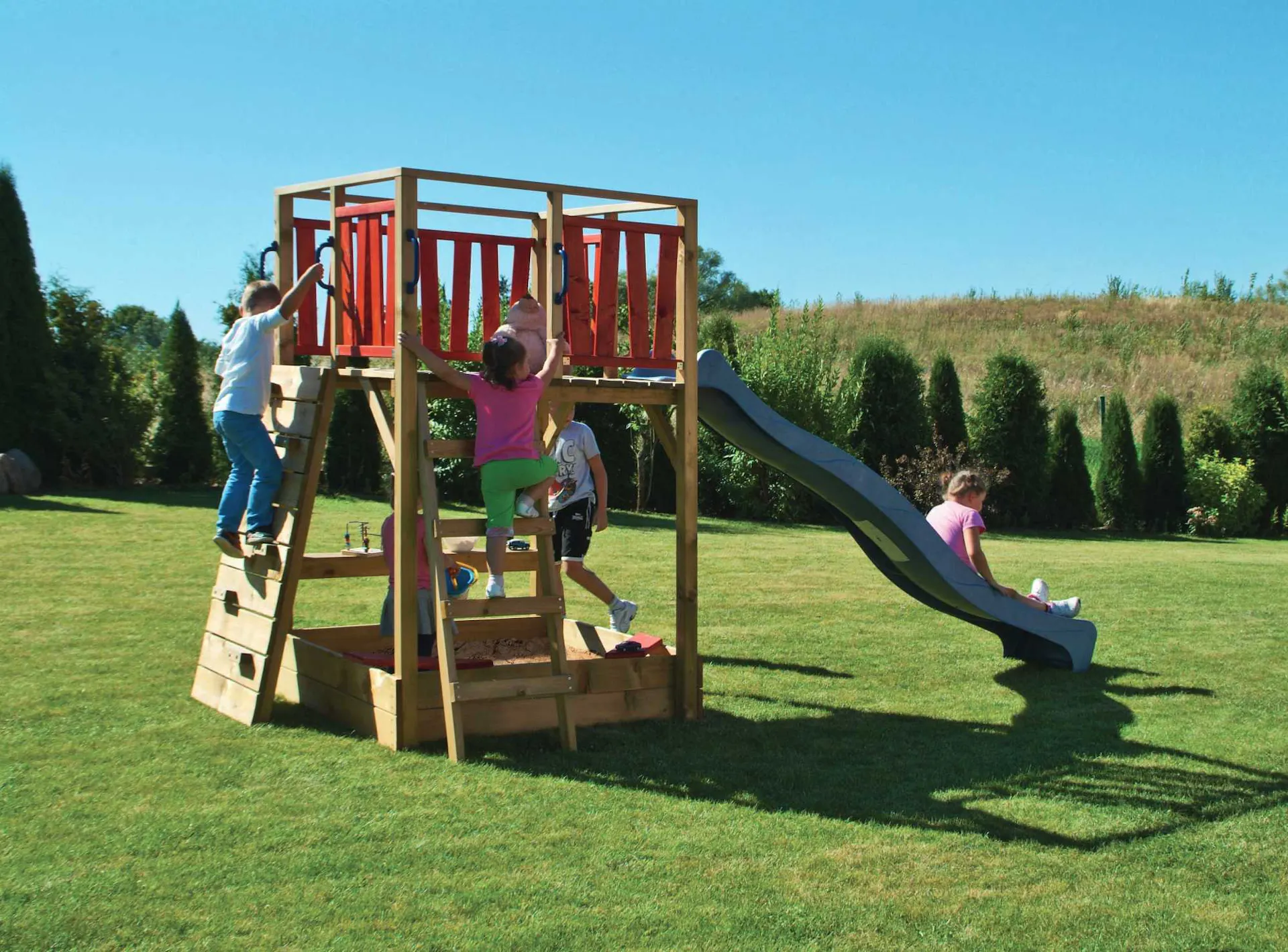 Bambini giocano sulla sabbiera modulare con scivolo e struttura per l’arrampicata.