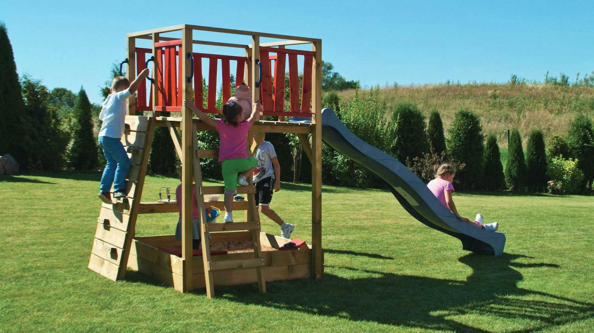 Kinder spielen auf Modul-Sandkasten mit Rutsche und Klettergerüst.