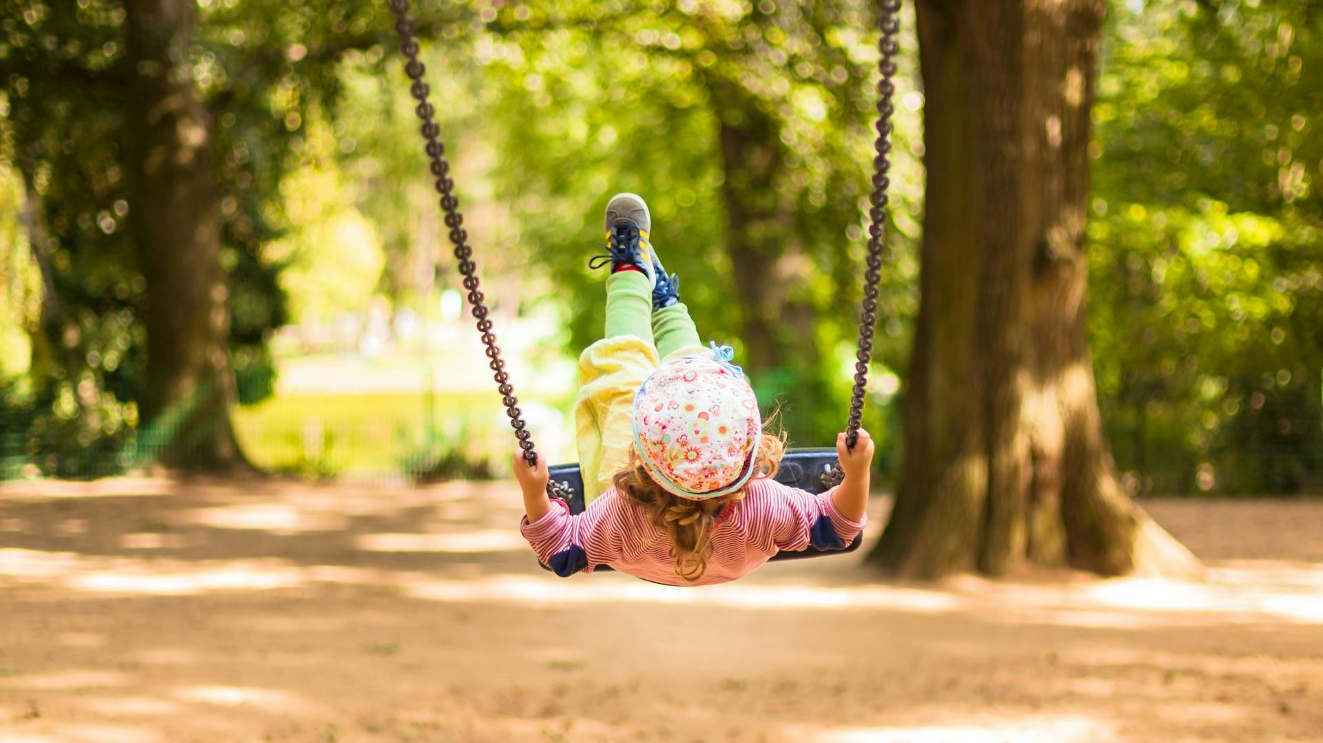 Mädchen auf Schaukel in Garten an Wald.
