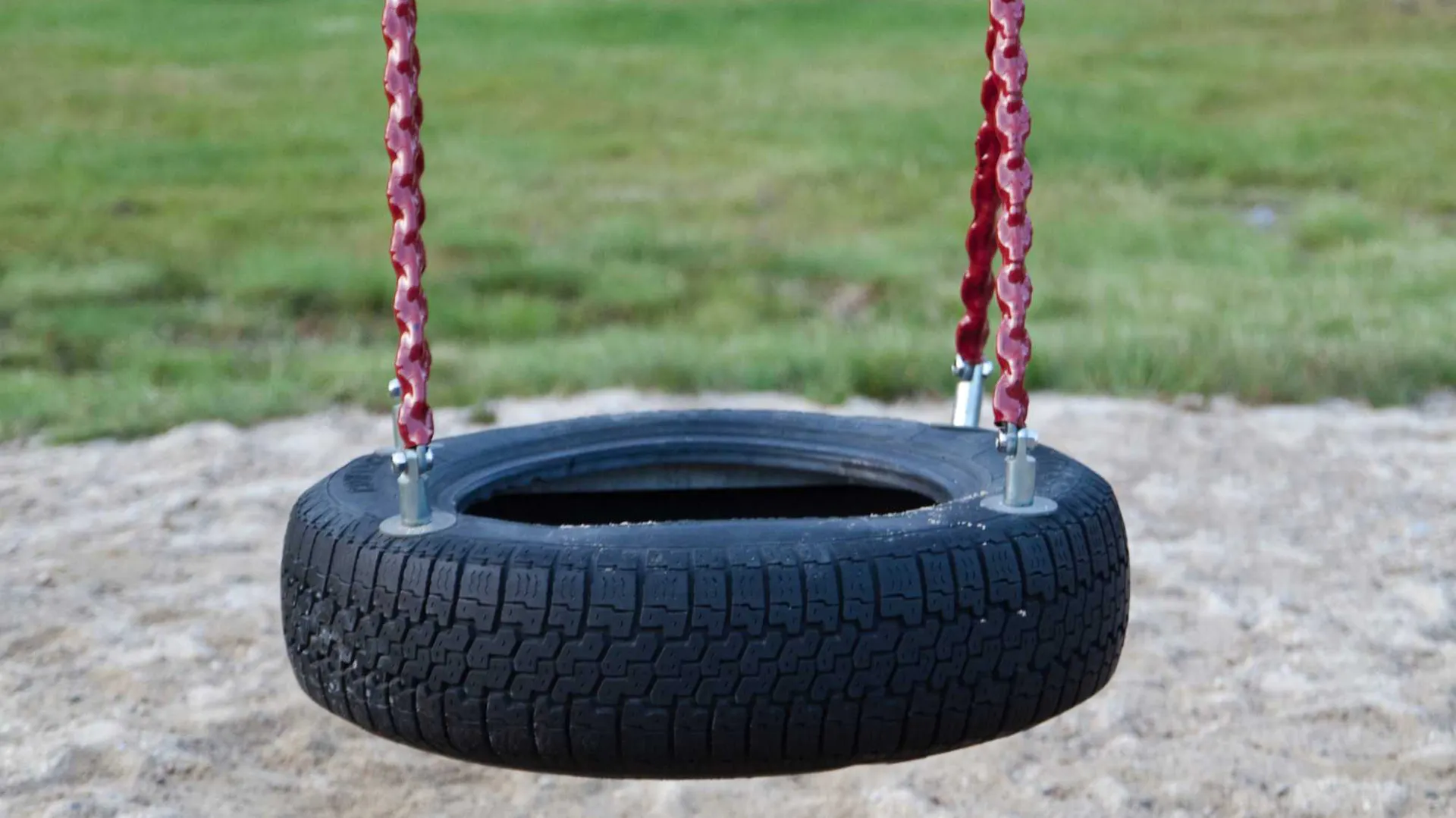 Altalena in pneumatici per auto appesa a corde rosse.