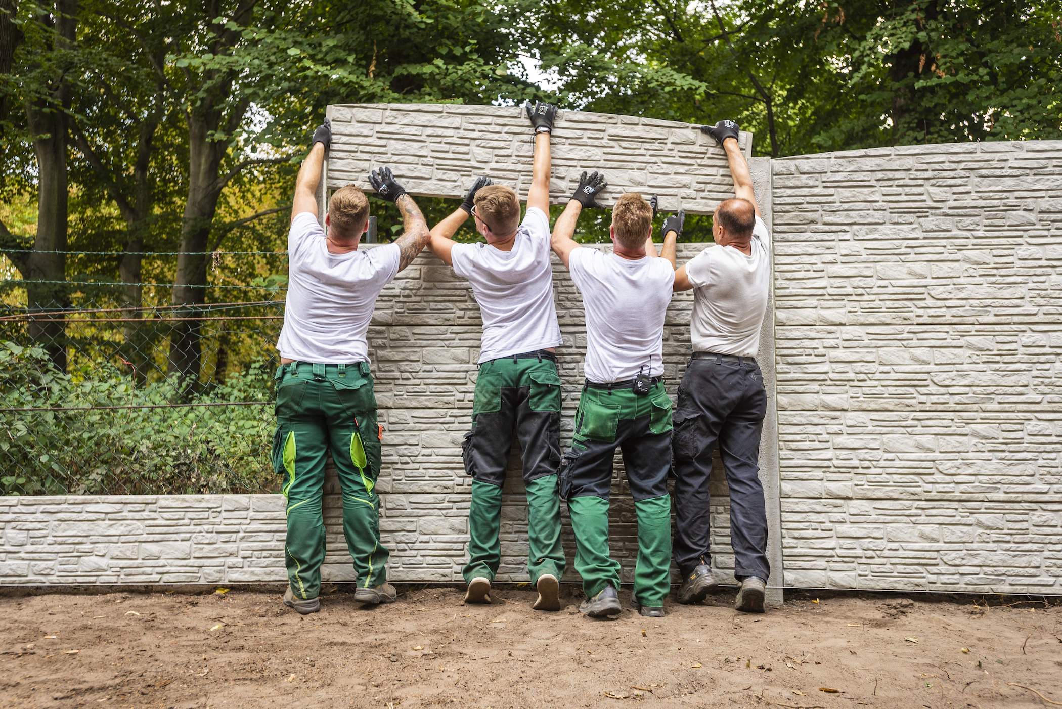 Handwerker bringen Mauer-Element an.